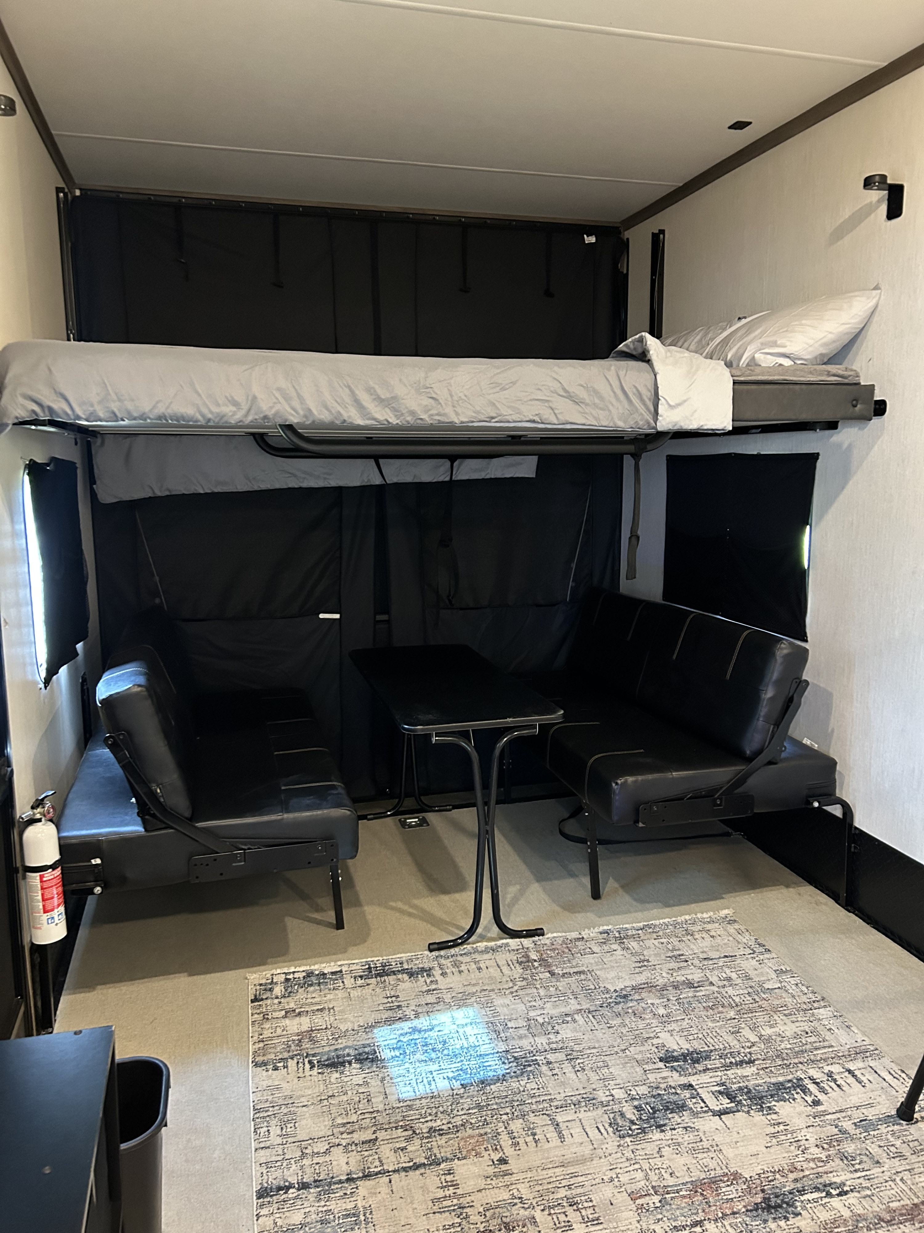 RV rental interior featuring a flexible living/sleeping space with a bunk bed, two convertible sofas, and a table.. Forest River Vengeance Vengeance Rogue Toy Hauler 2022