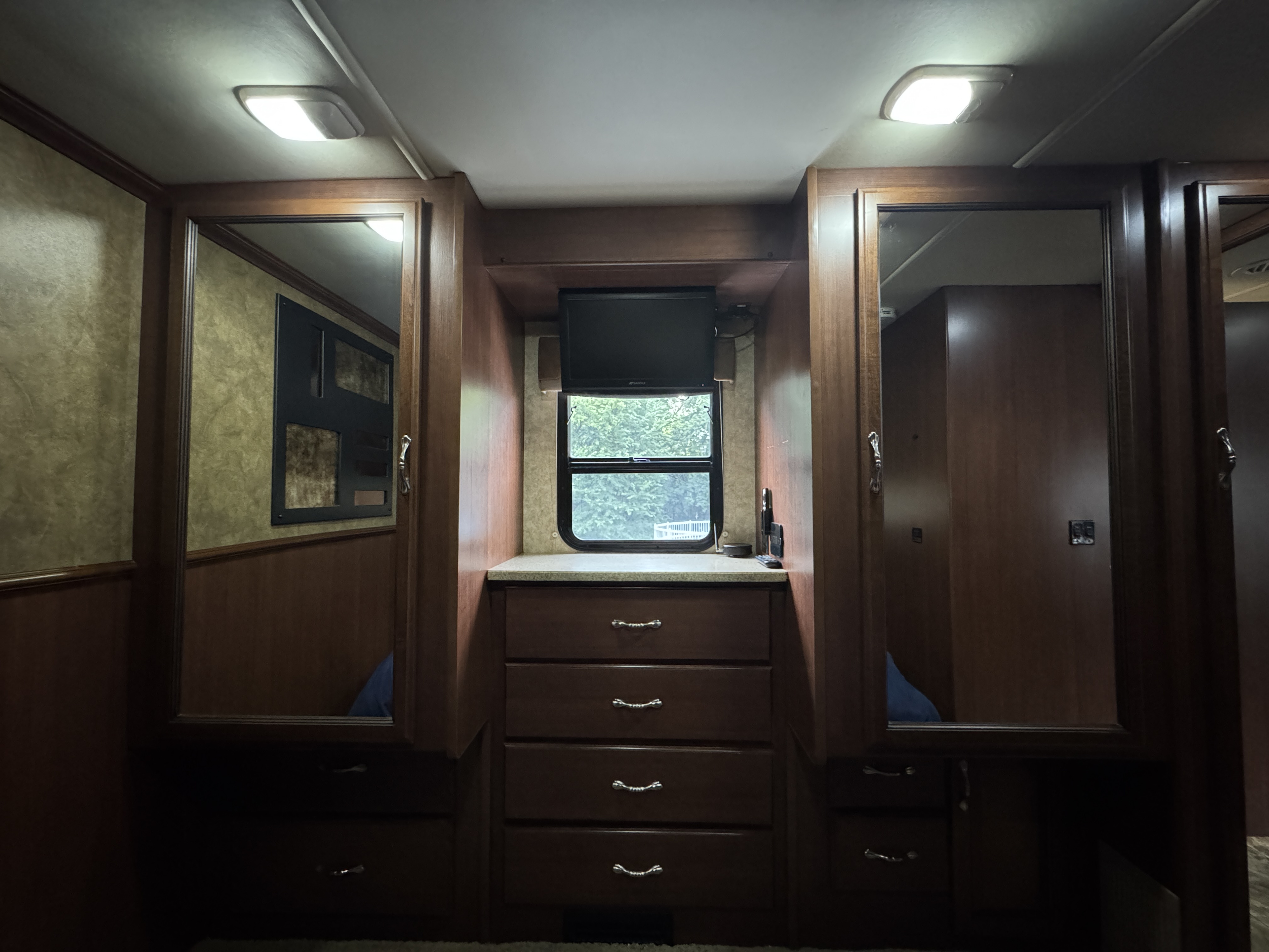 RV rental bedroom: mirrored wardrobes, central dresser, TV, and window view offer comfort and storage.. Bounder Classic 2013