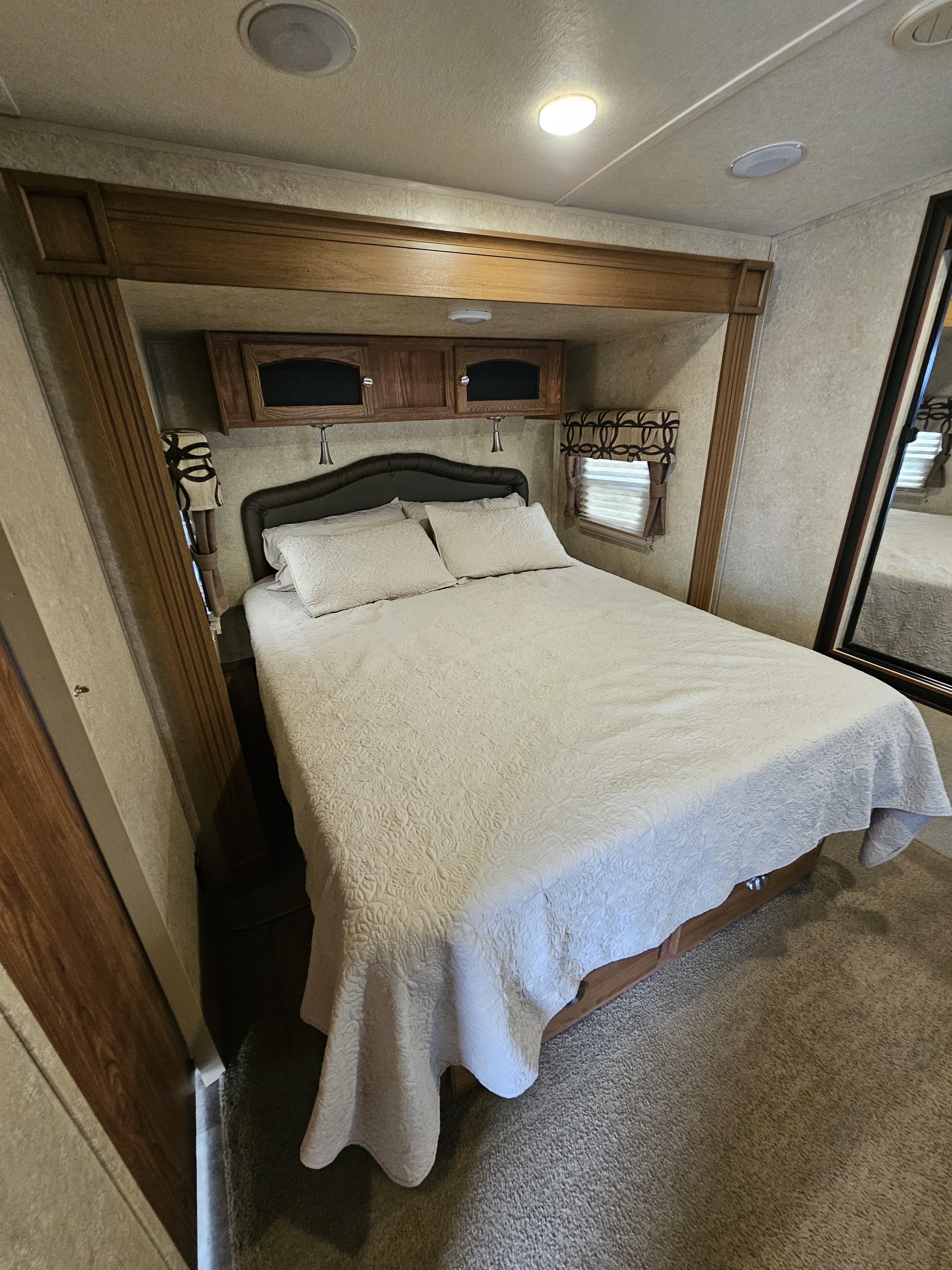 This image shows a cozy RV bedroom with a comfortable bed, cabinets, and window, perfect for your next RV rental adventure.. Forest River Flagstaff Classic Super Lite 2016