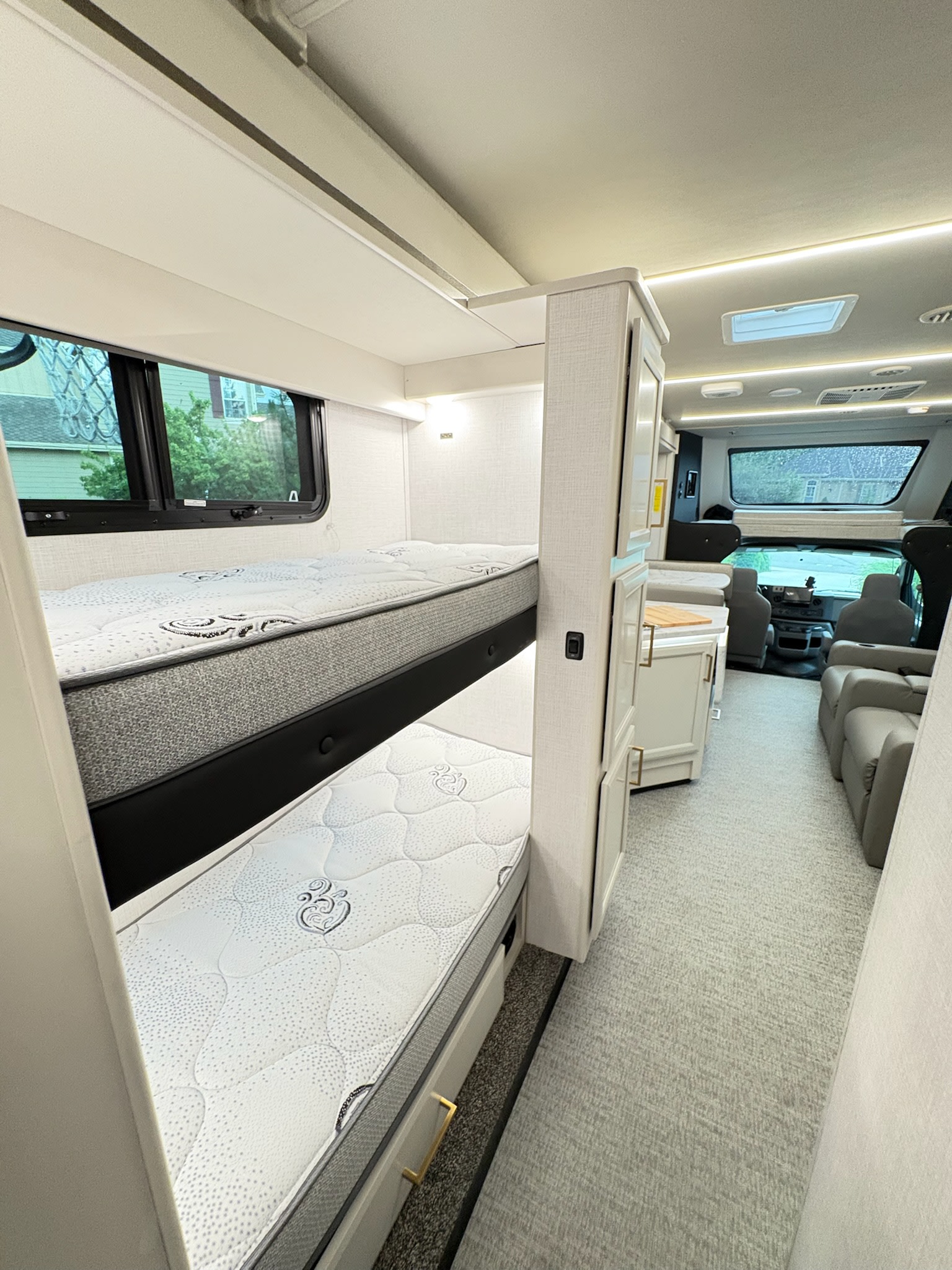 Explore this modern RV rental interior featuring comfortable bunk beds, a functional kitchenette, and ample seating.. Fleetwood Altitude 31W 2026