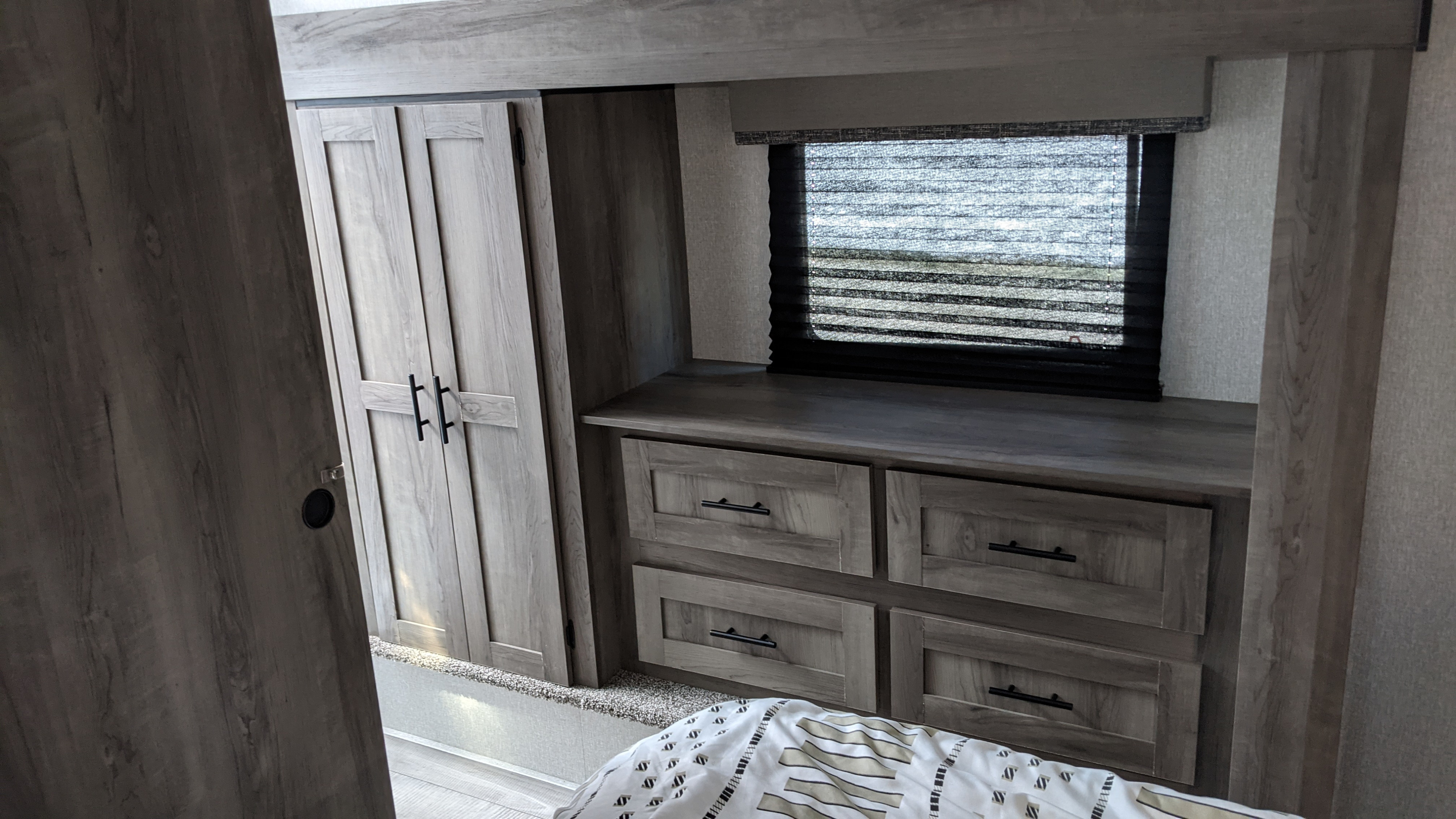 This RV rental bedroom features a built-in wardrobe, ample dresser storage, and window, perfect for your travels.. KZ Sportsman 292BHK 2021