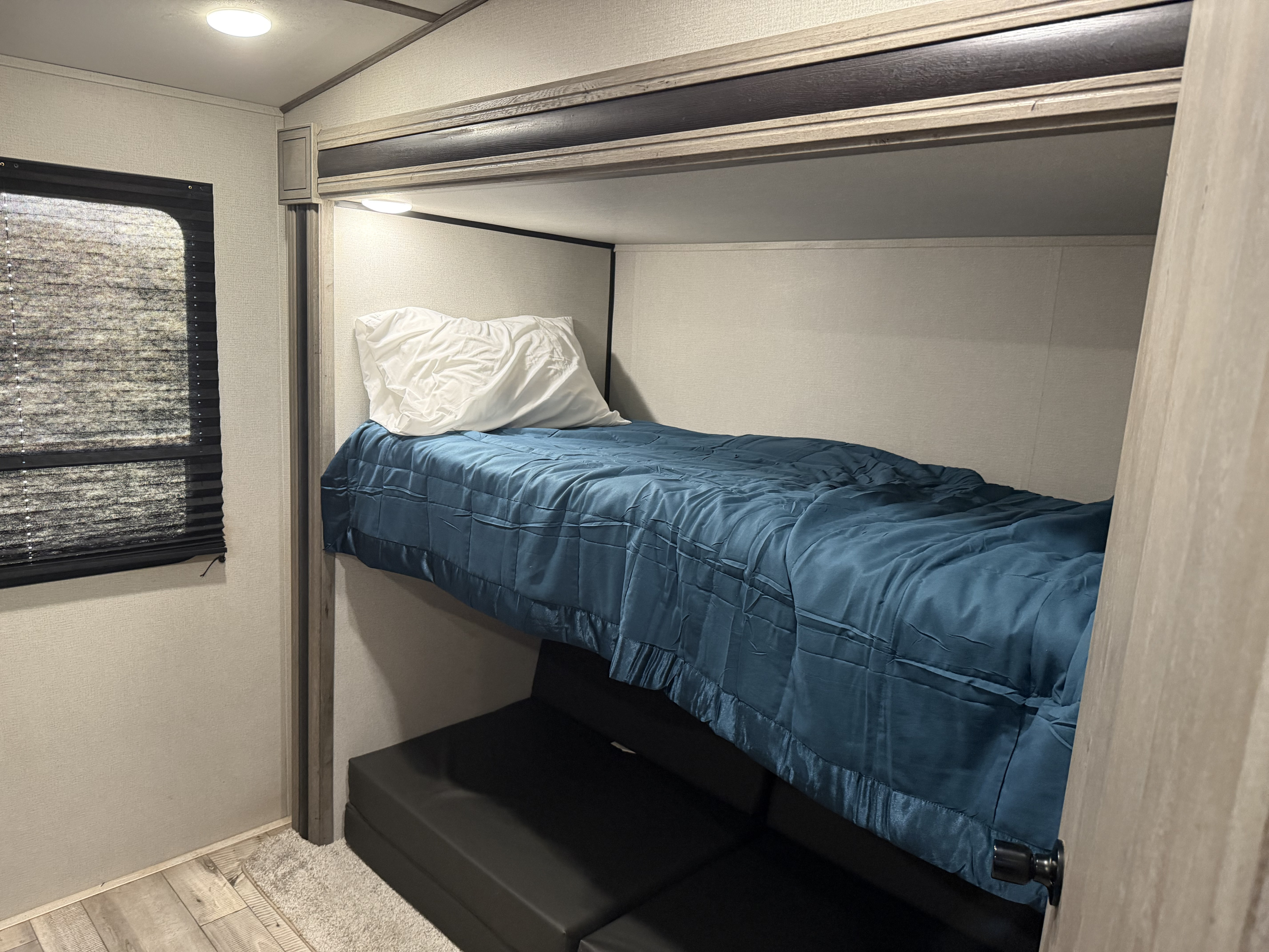 RV rental interior: Comfortable bunk bed with blue comforter & lower convertible sleeping space.. Keystone RV Springdale 2021