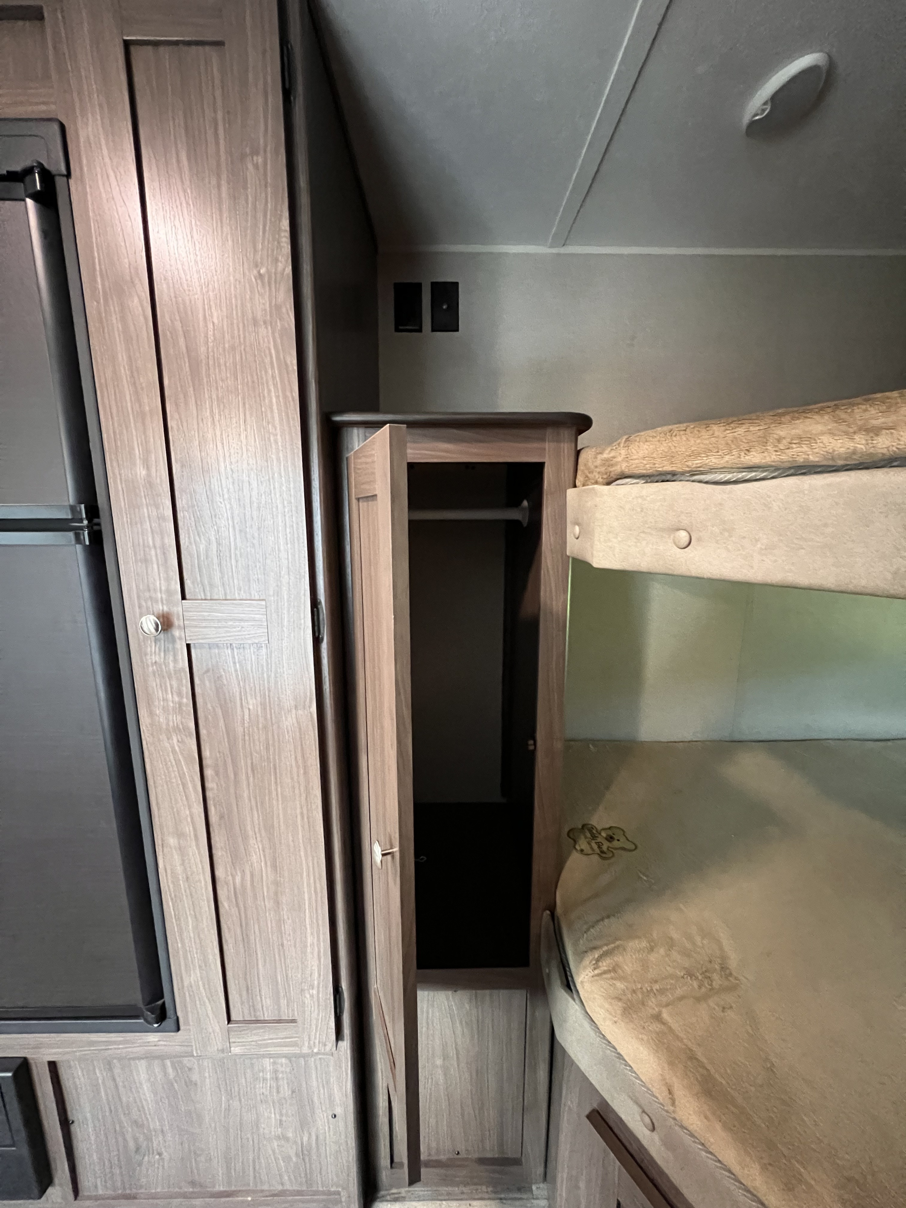 This RV rental interior features a fridge, open wardrobe for storage, wall outlets, and practical bunk beds.. Keystone RV Hideout 2018