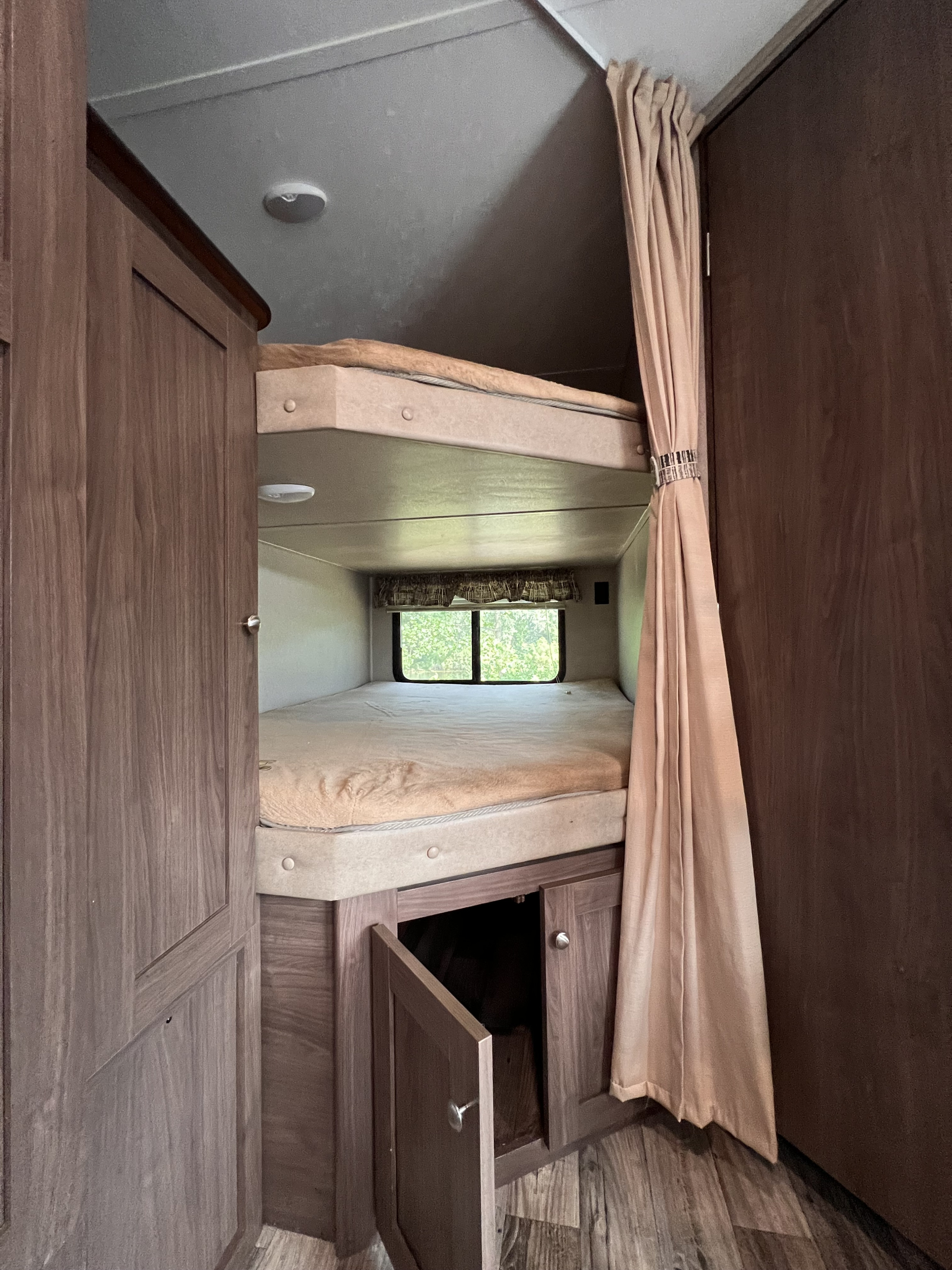 Cozy RV rental bunk beds with window view, perfect for family travel. Includes wardrobe and under-bunk storage.. Keystone RV Hideout 2018
