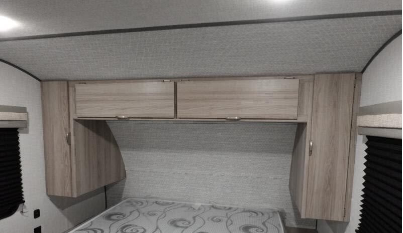 View of an RV rental bedroom with light wood storage cabinets above the bed, offering ample space.. Forest River Salem 266BHLE 2025