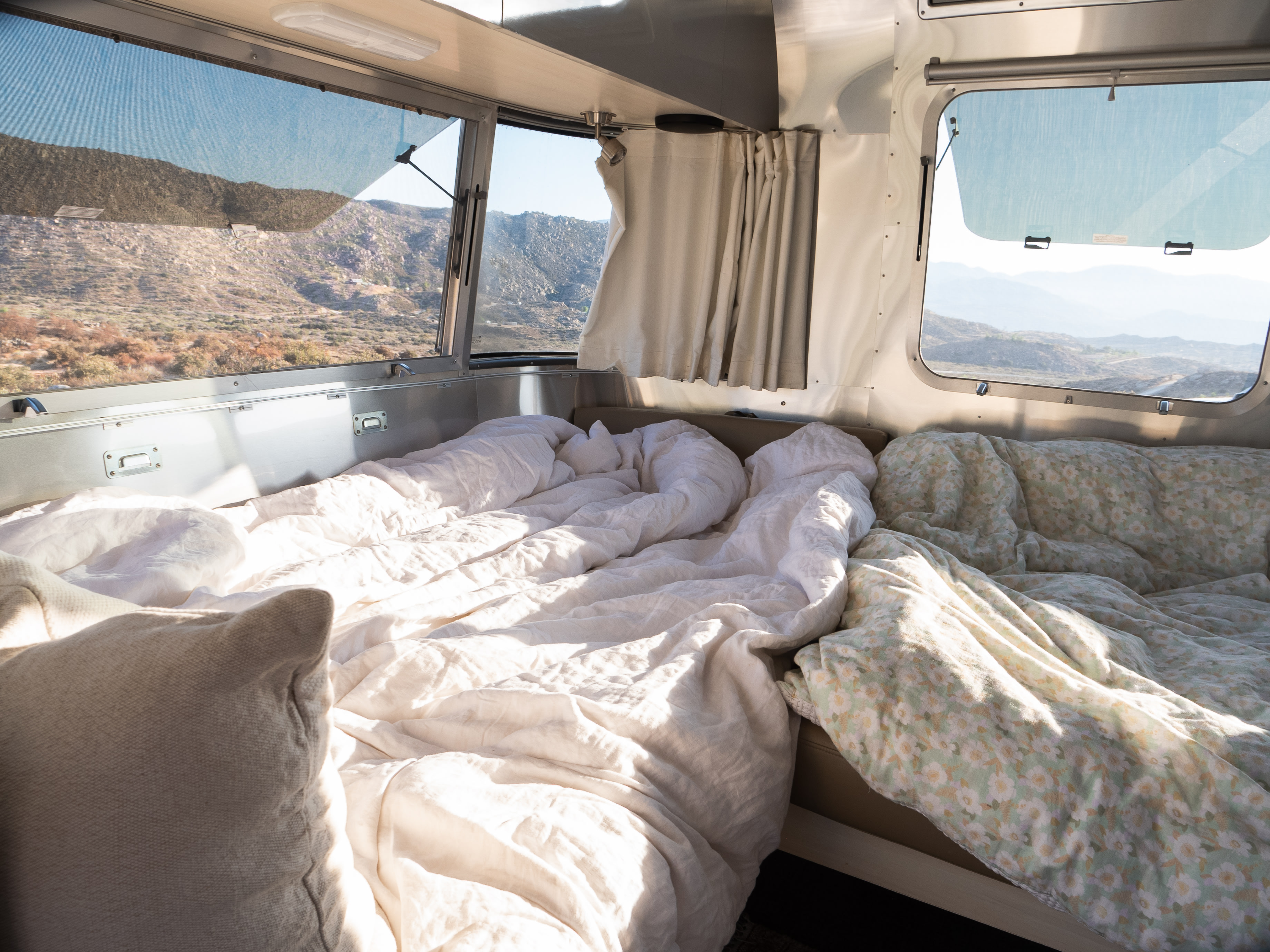 Cozy RV rental interior with a soft bed and panoramic mountain views, perfect for a scenic escape.. Airstream Flying Cloud 2022