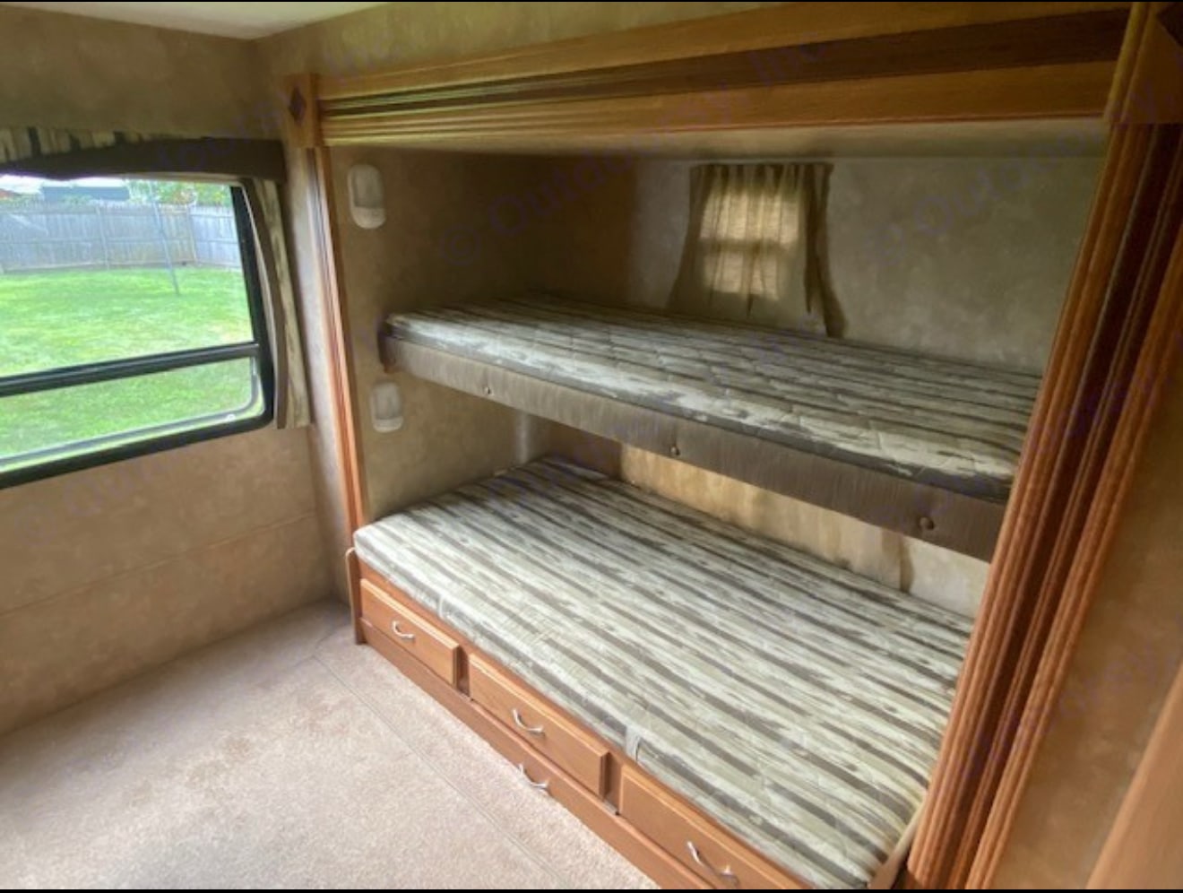 Inside RV rental: bunk beds with striped mattresses, wood drawers, & a window showing a green yard.. Jayco Jay Flight G2 2009
