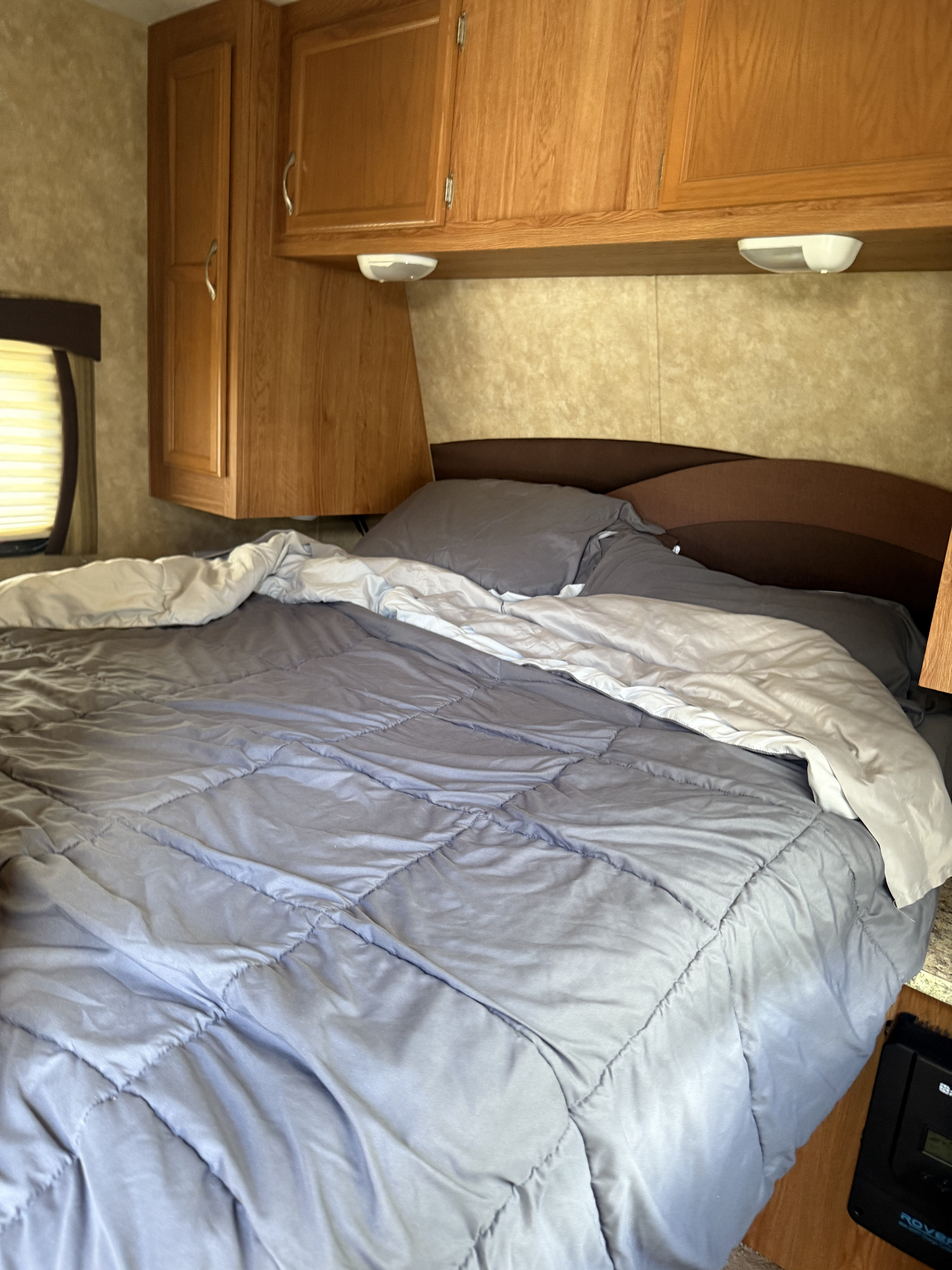 Cozy RV rental bedroom with a bed, gray comforter, wood cabinets, and an illuminated window, ready for your trip.. Jayco Jay Flight G2 2009