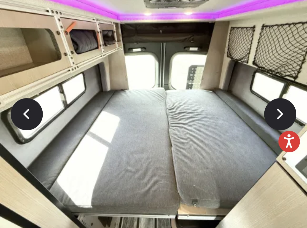 Inside an rv rental, a cozy bed fills the rear, flanked by windows and overhead storage with purple LED lighting.. Antero Adventure Motors Antero Adventure Motors Class B 2022
