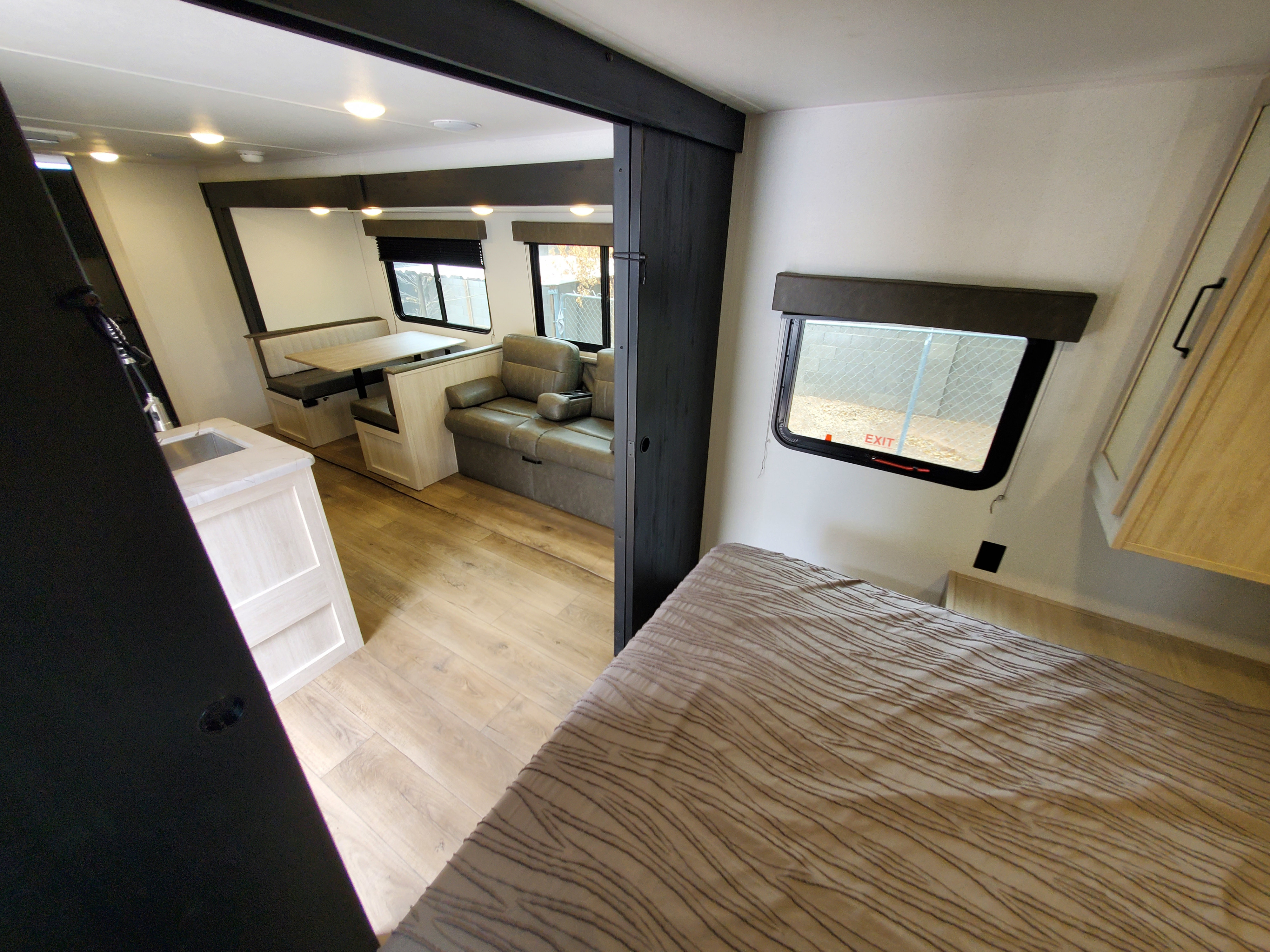 RV rental interior with bedroom, dining booth, comfy sofa, and kitchen area, perfect for your next adventure.. forest river Puma 2025