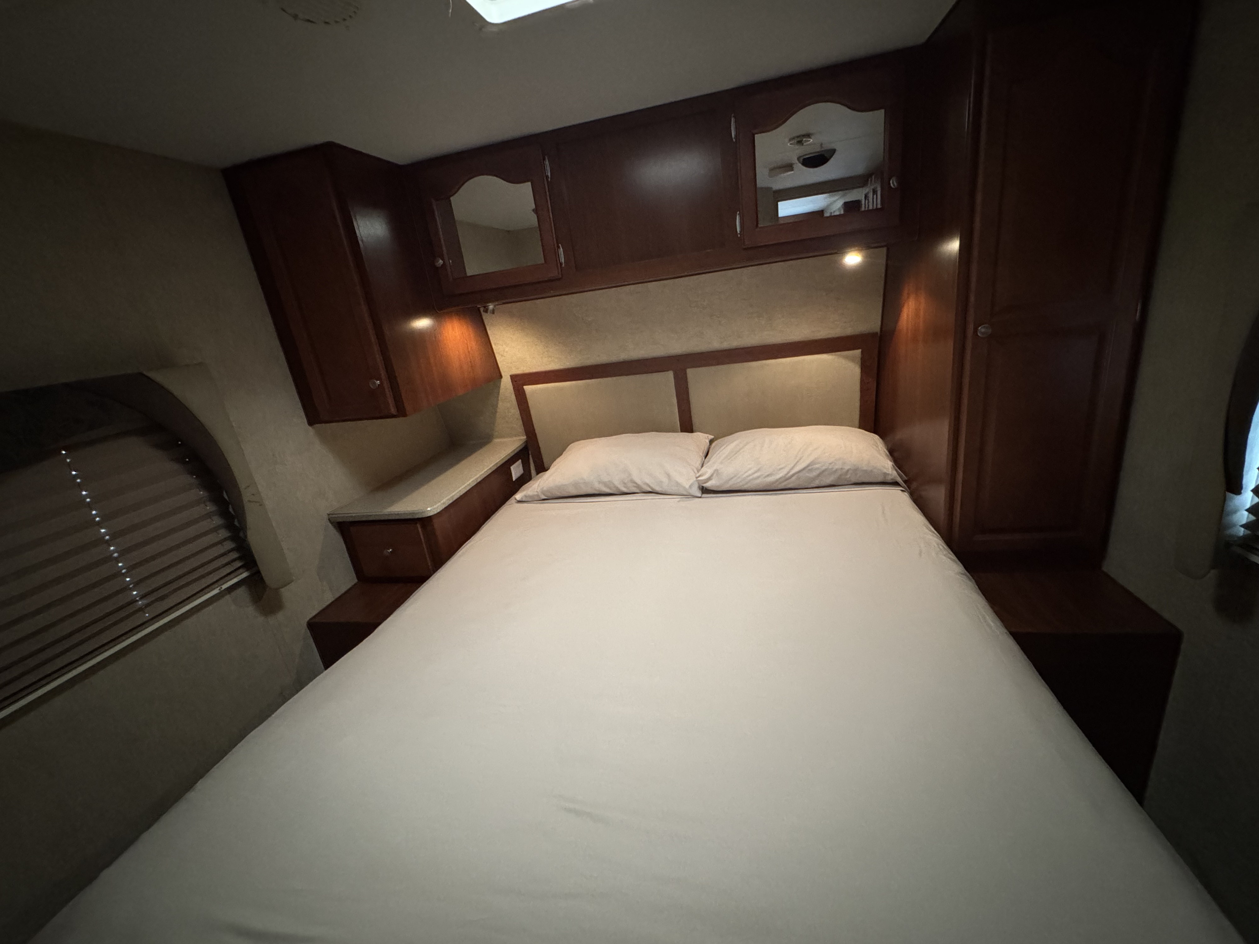 Well-appointed RV rental bedroom with a large bed, integrated storage, and inviting overhead lighting.. Fleetwood Prowler 2009