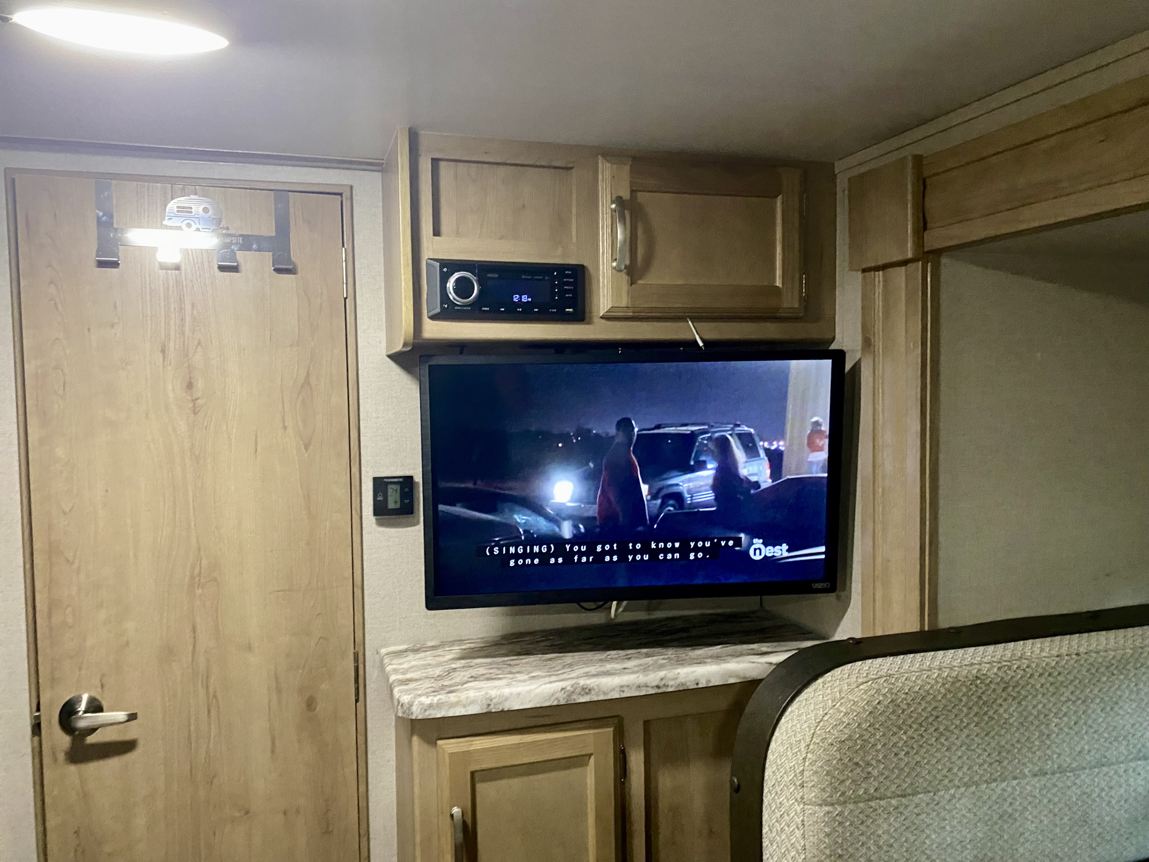 Cozy RV rental interior featuring a TV displaying closed captions, a stereo, and thermostat, ideal for comfortable travel.. Winnebago Minnie Winnie 2020