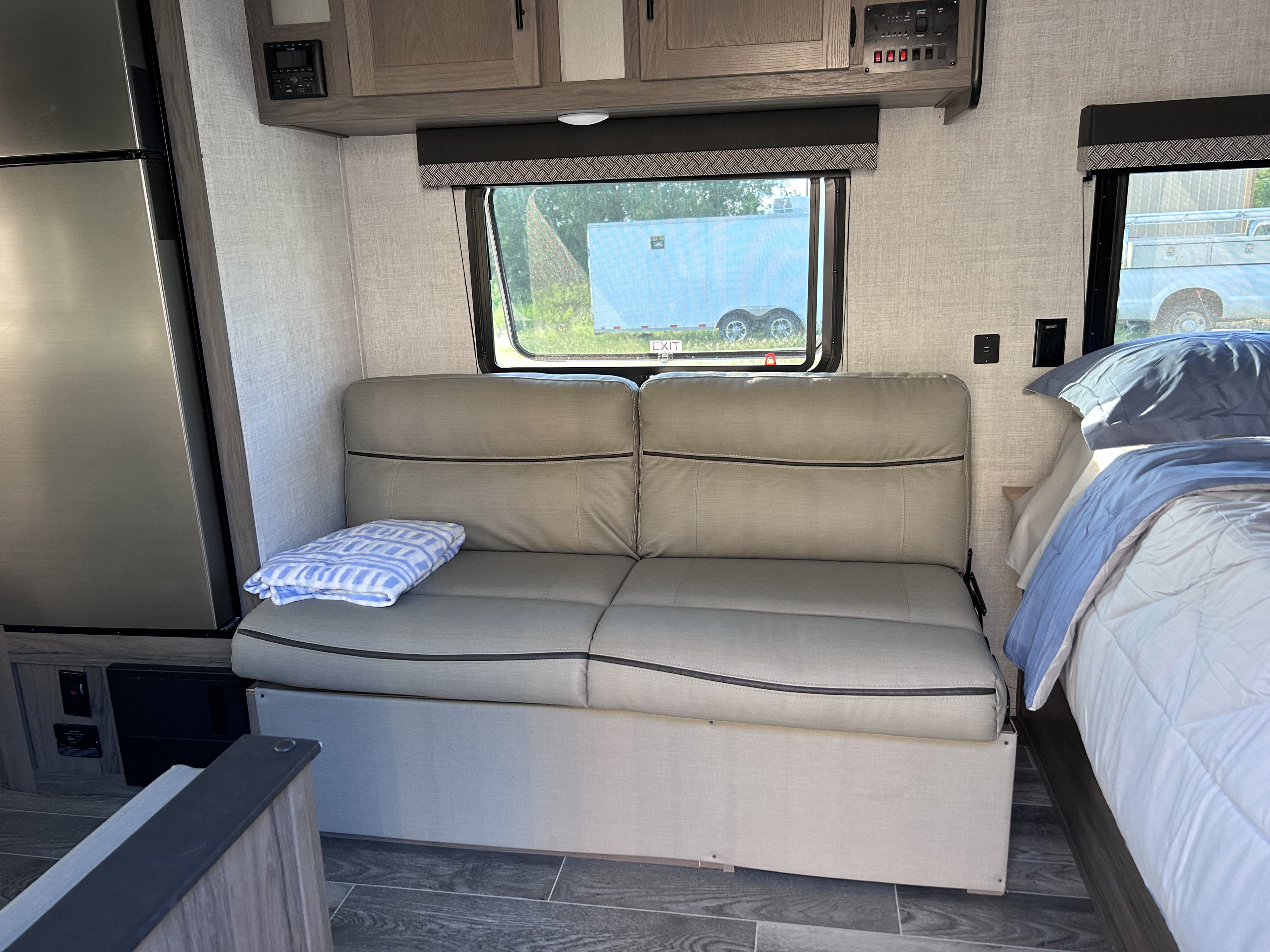 Spacious RV rental interior with a cozy sofa, large fridge, overhead cabinets, and a comfortable bed, ready for adventures.. Gulf Stream Ameri-Lite 2022