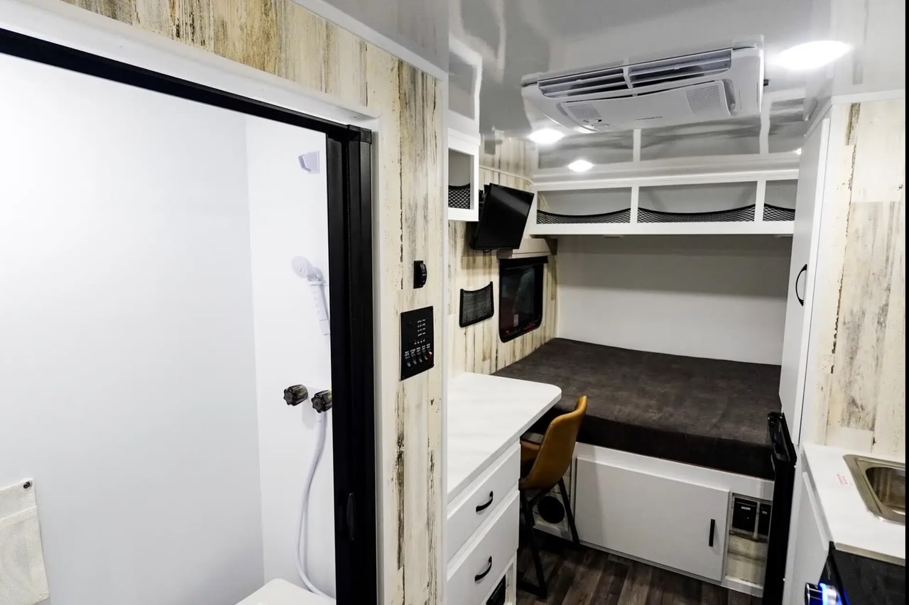 Bright RV rental interior showing a shower, bed, desk, kitchen area, and ample storage. Your adventure awaits!. Modern Buggy RV Country Born CB16 2025