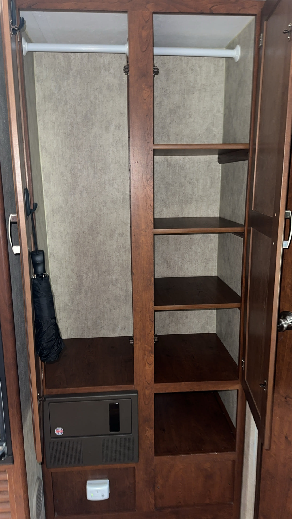 RV rental wardrobe with hanging rod, multi-level shelves, and an electrical panel, offering practical storage solutions.. Keystone RV Passport Ultra Lite 2015
