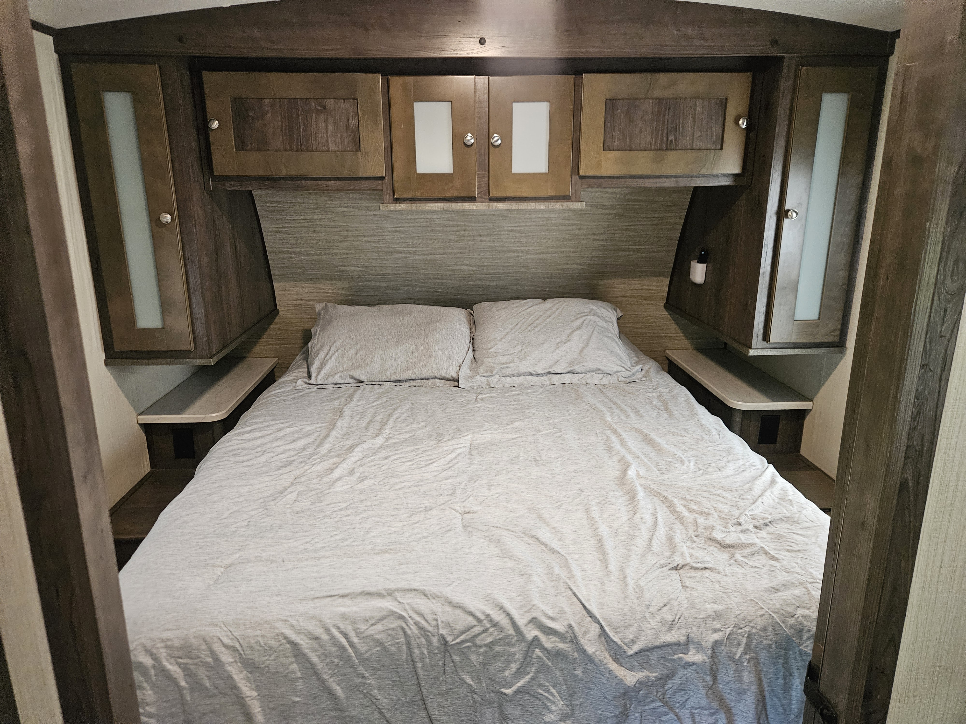 RV rental interior: a cozy bedroom with a bed, pillows, overhead cabinets, and convenient side shelving for comfort.. Cruiser RV MPG Ultra Lite 2020