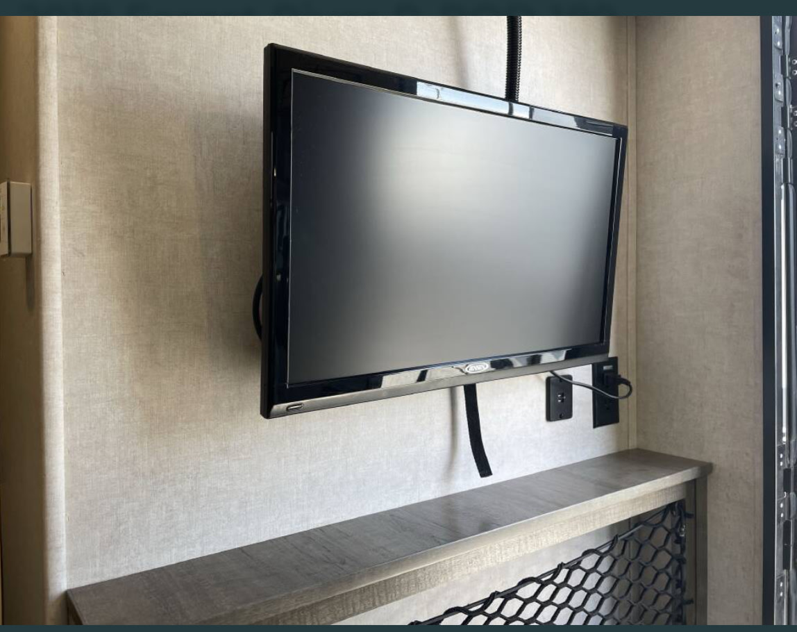RV rental interior: wall-mounted TV, outlets, and a shelf with mesh storage, perfect for compact travel.. R-Pod R-Pod Trailer 2018