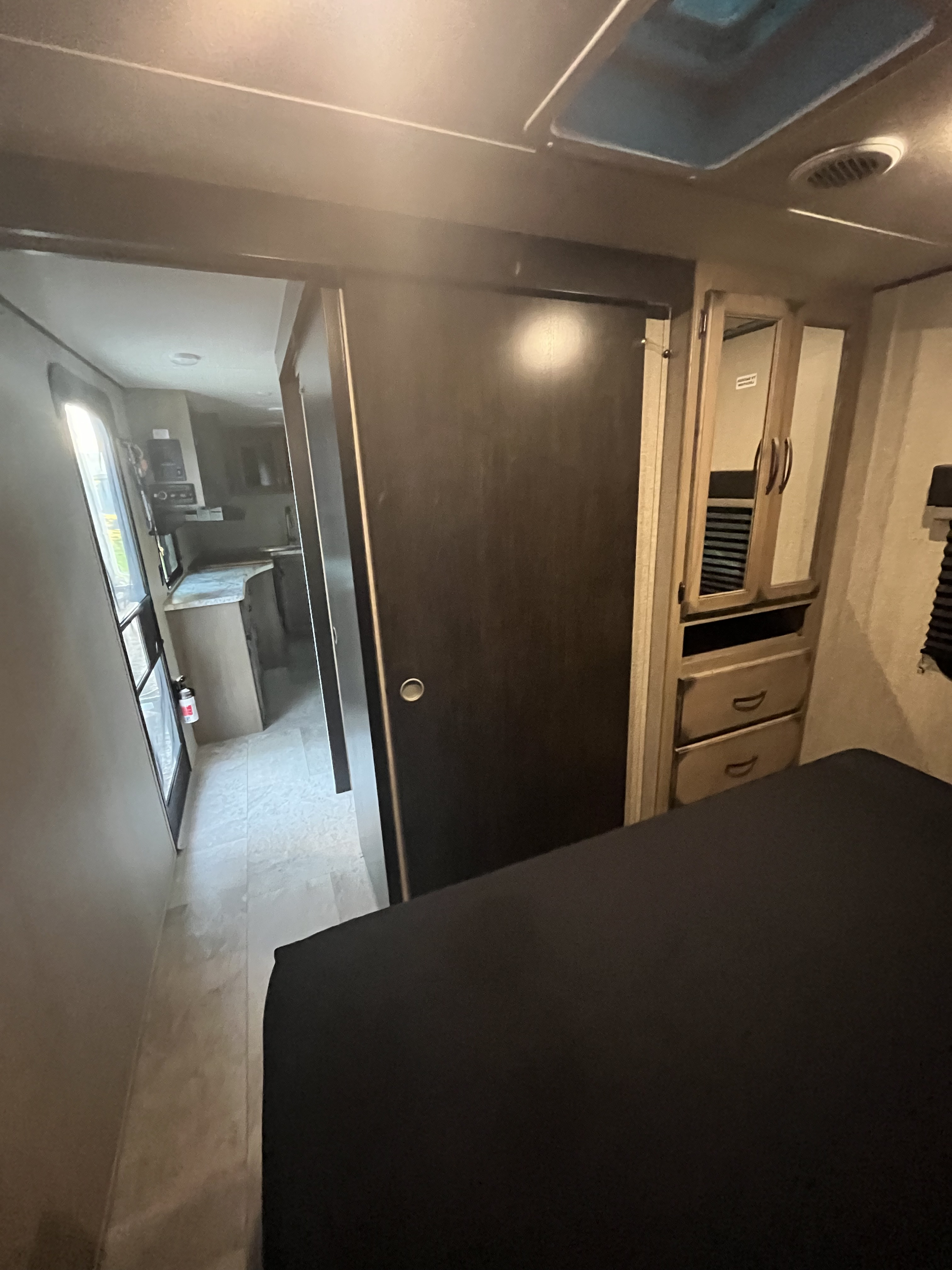 Spacious RV rental interior: bedroom with skylight, wardrobe, and sliding door to kitchen area.. Grand Design Transcend Xplor 2020