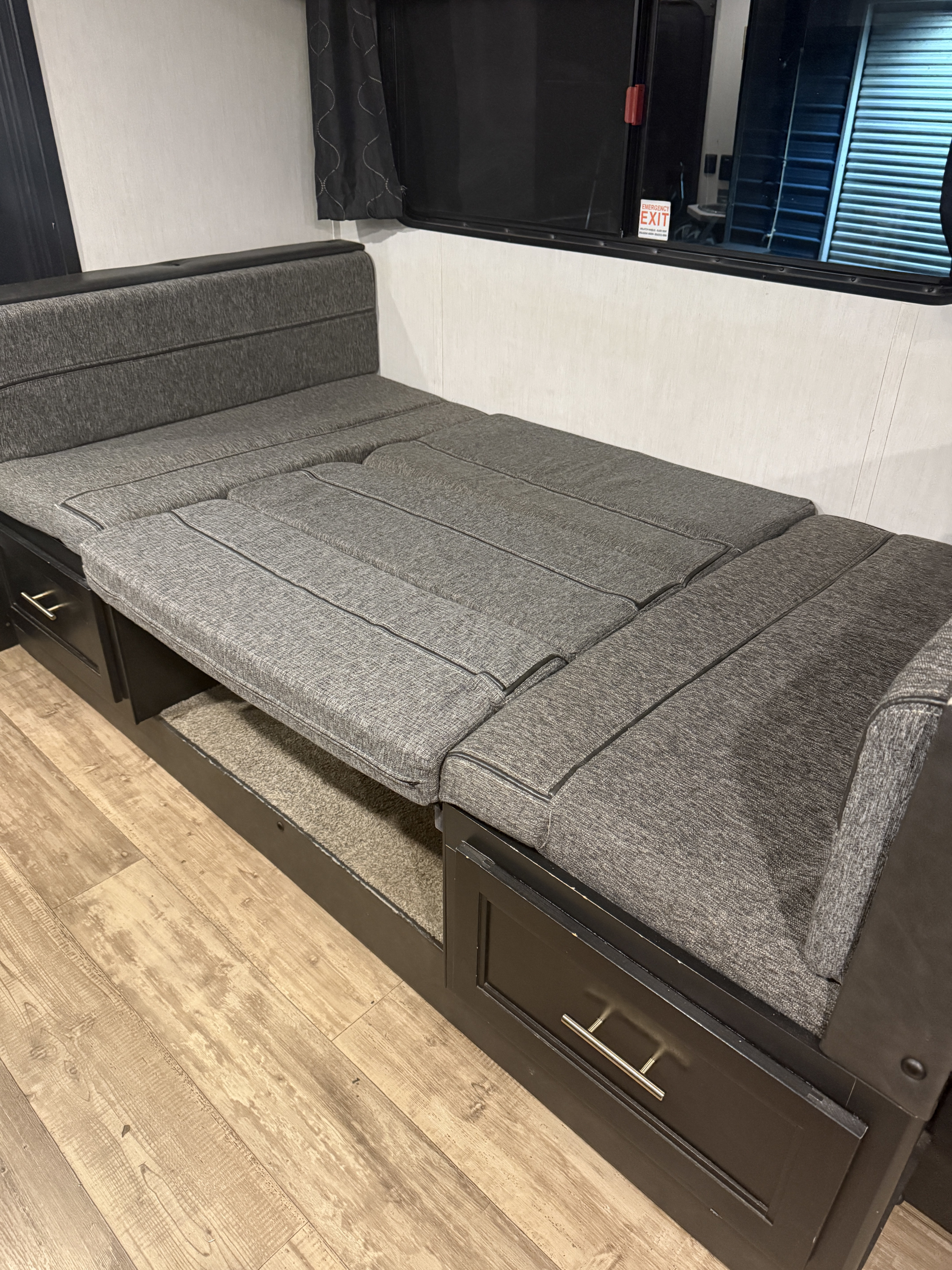 This RV rental features a gray fabric sofa bed, extended for sleeping. It's a versatile interior with storage drawers and wood flooring.. Forest River Cherokee Grey Wolf 2022