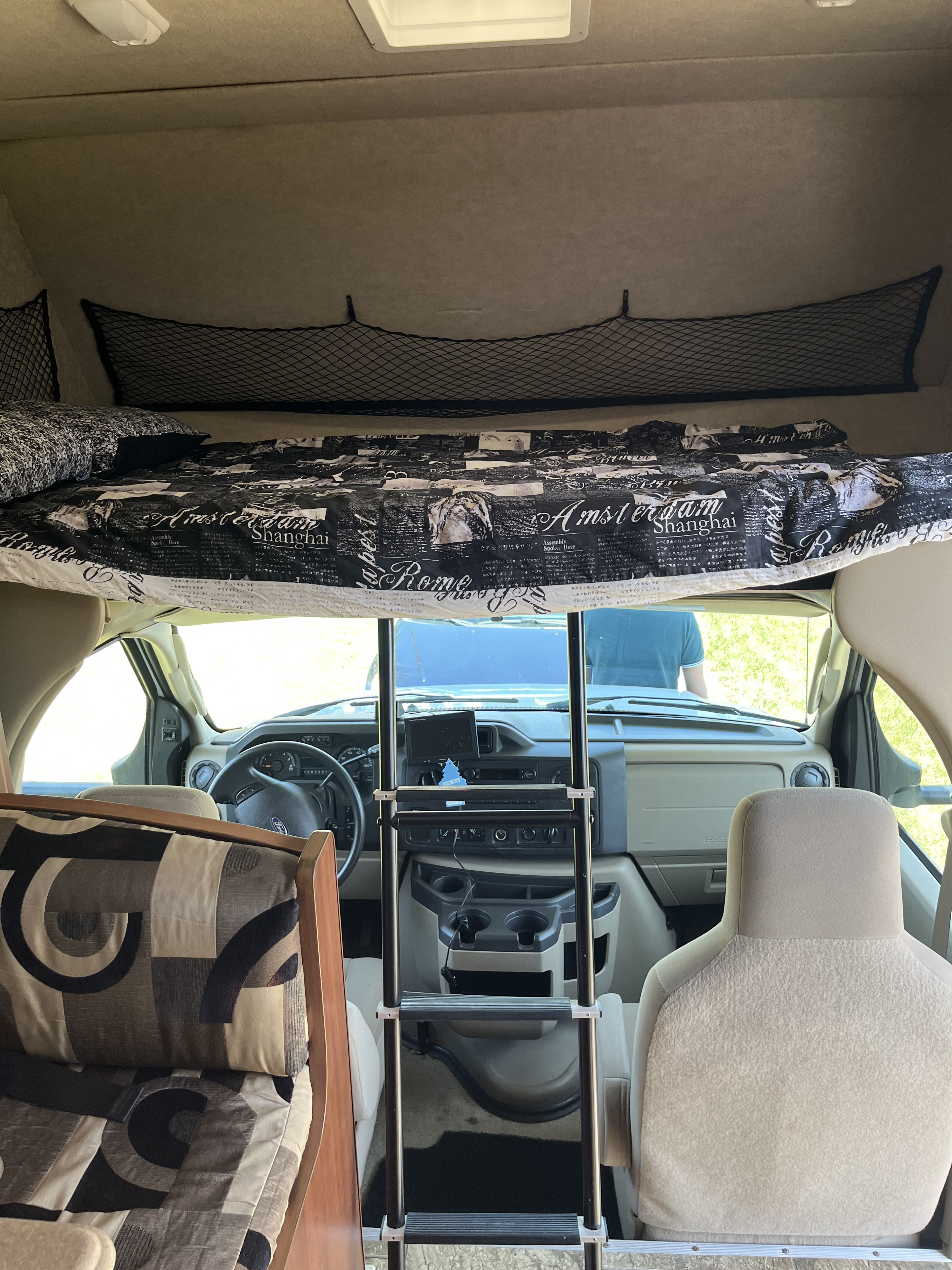 RV rental interior shows an overhead bunk with city-themed bedding, ladder, and the driver's cab.. Tioga Montara 2012