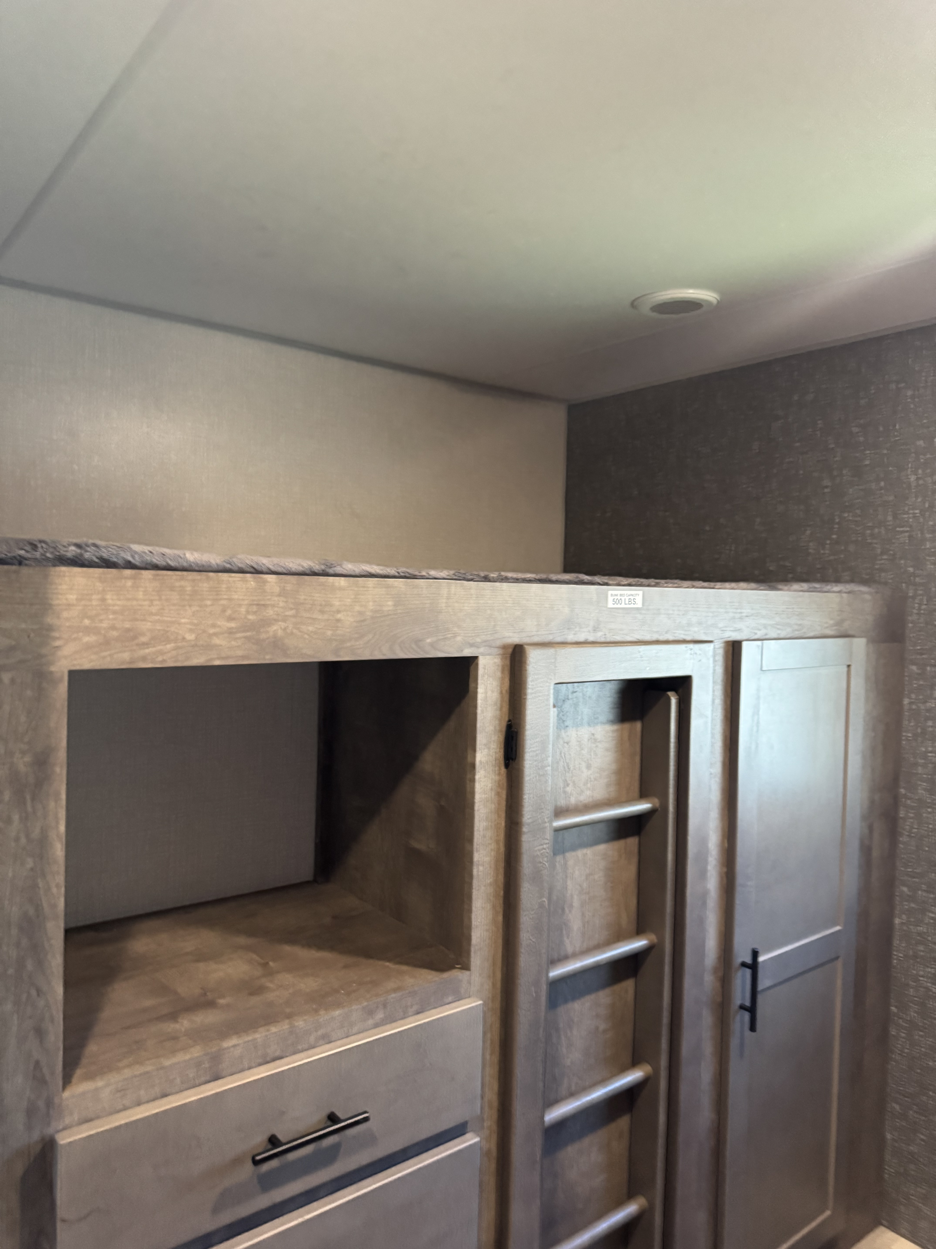 RV rental interior: A sturdy bunk bed with integrated storage, shelving, and cabinets below, featuring a ladder and drawers.. KZ Connect 2021
