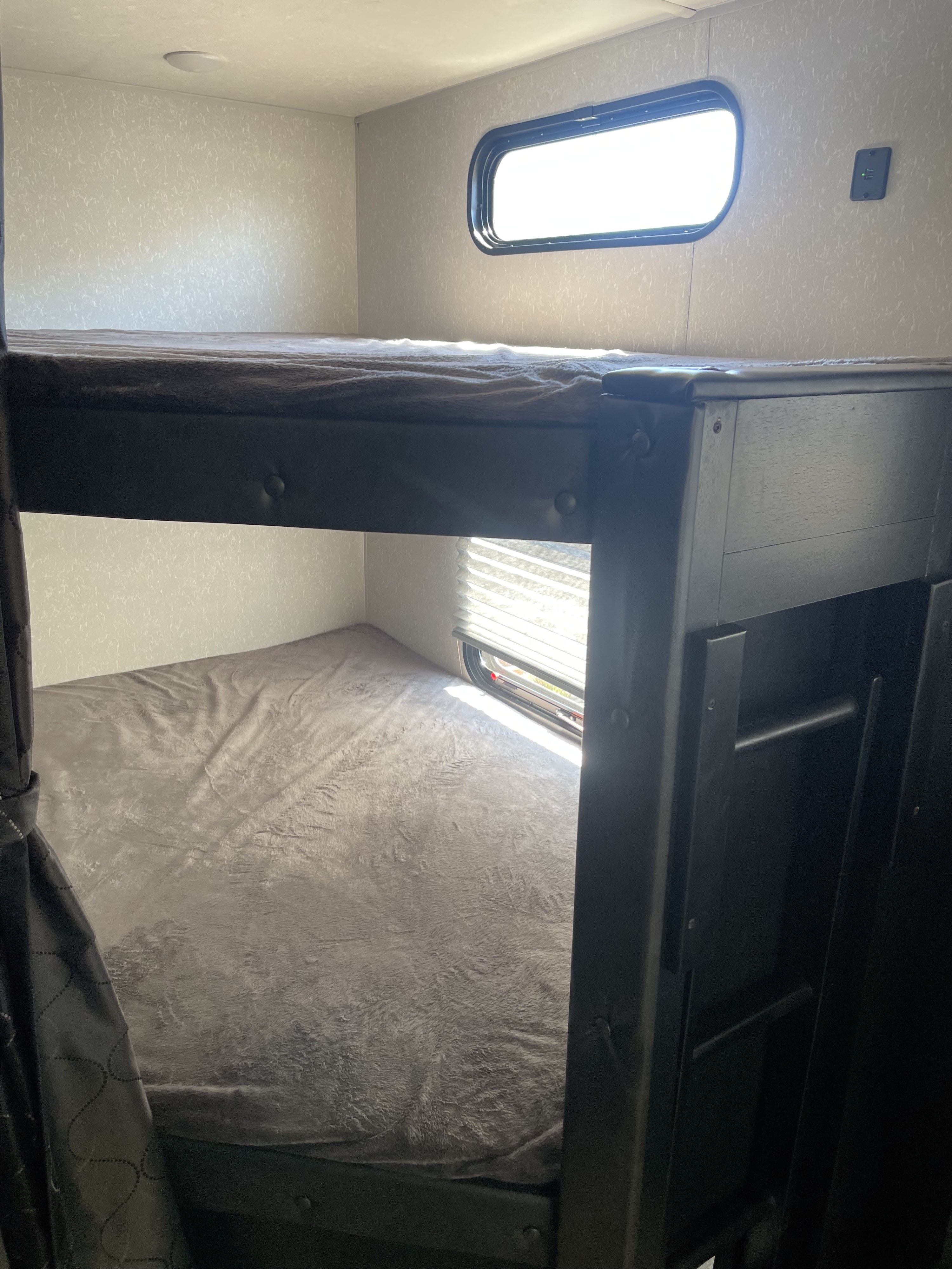 Cozy RV rental bunk beds with window views and USB charging, ready for comfortable travel adventures.. Forest River Cherokee Grey Wolf 2021