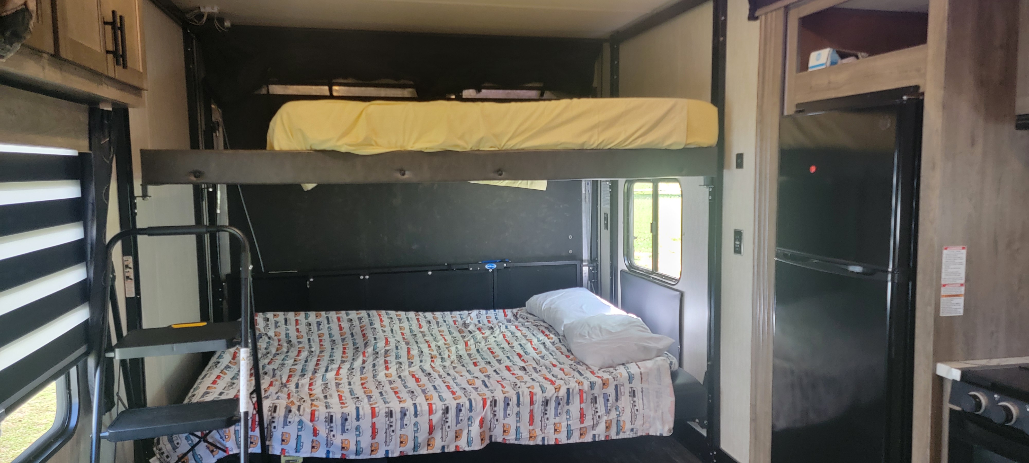 RV rental interior shows bunk beds with a ladder, refrigerator, and cabinet storage for comfortable travel.. Forest River Cherokee Wolf Pack 2021
