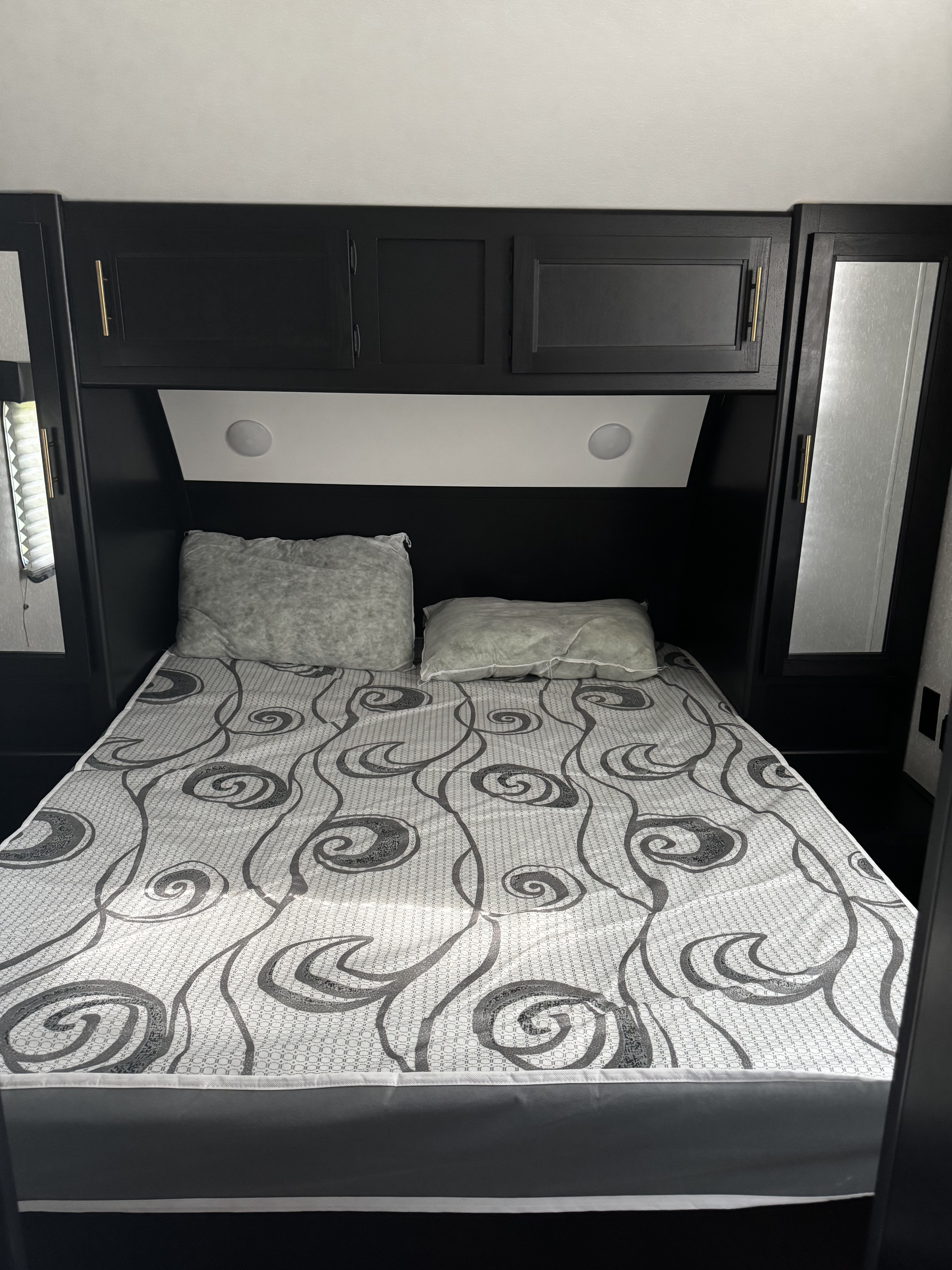 Compact RV rental bedroom featuring a bed, storage, and lighting for comfortable travel.. Forest River Cherokee Grey Wolf 2022
