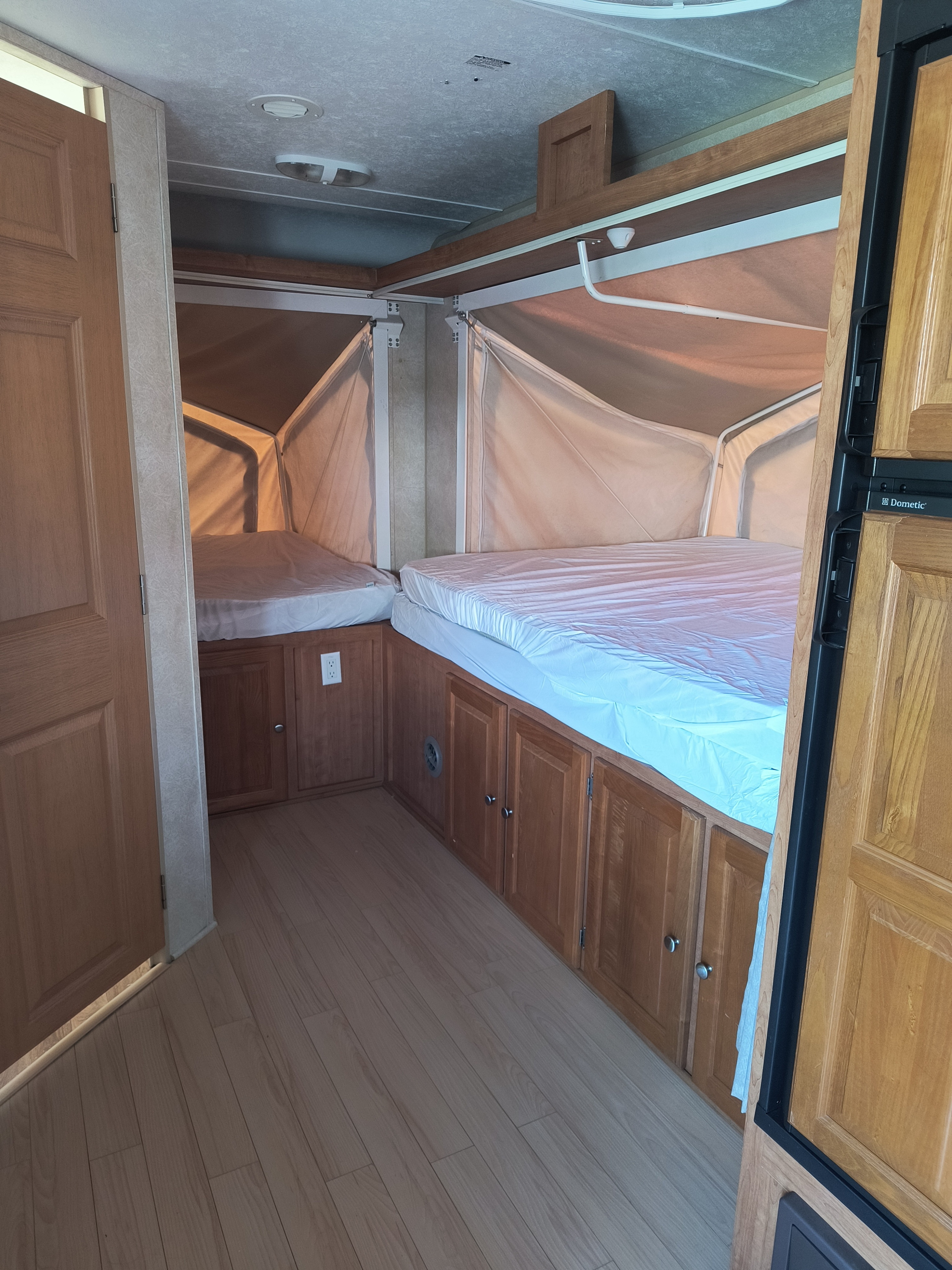 Inside an RV rental featuring two comfortable pop-out beds with white sheets, wooden cabinetry, and light wood flooring.. Forest River Flagstaff Shamrock 2009