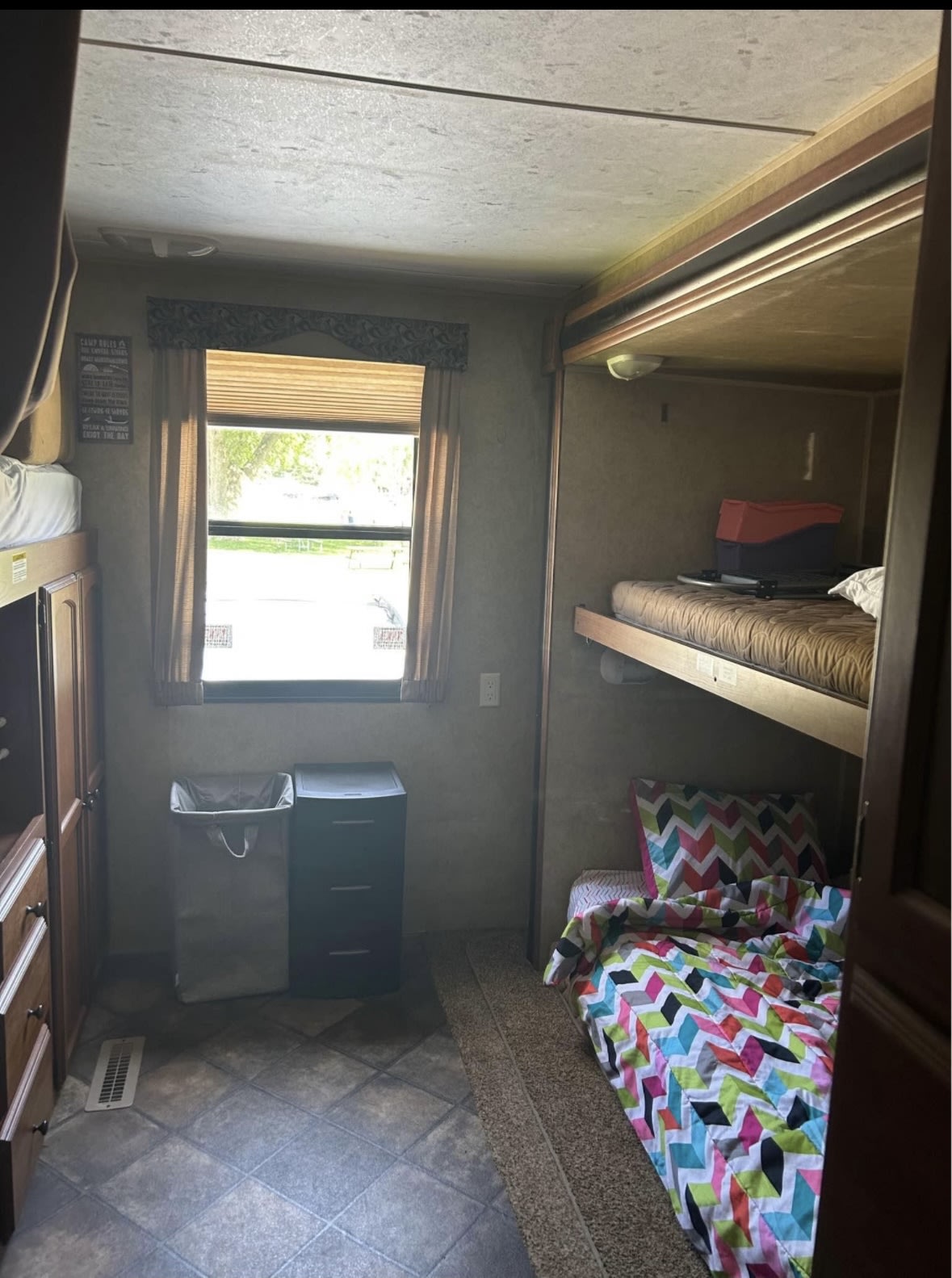 An RV rental bedroom with multiple bunk beds, a central window, and storage cabinets, offering family sleeping space.. Dutchmen Dutchmen Trailer 2013