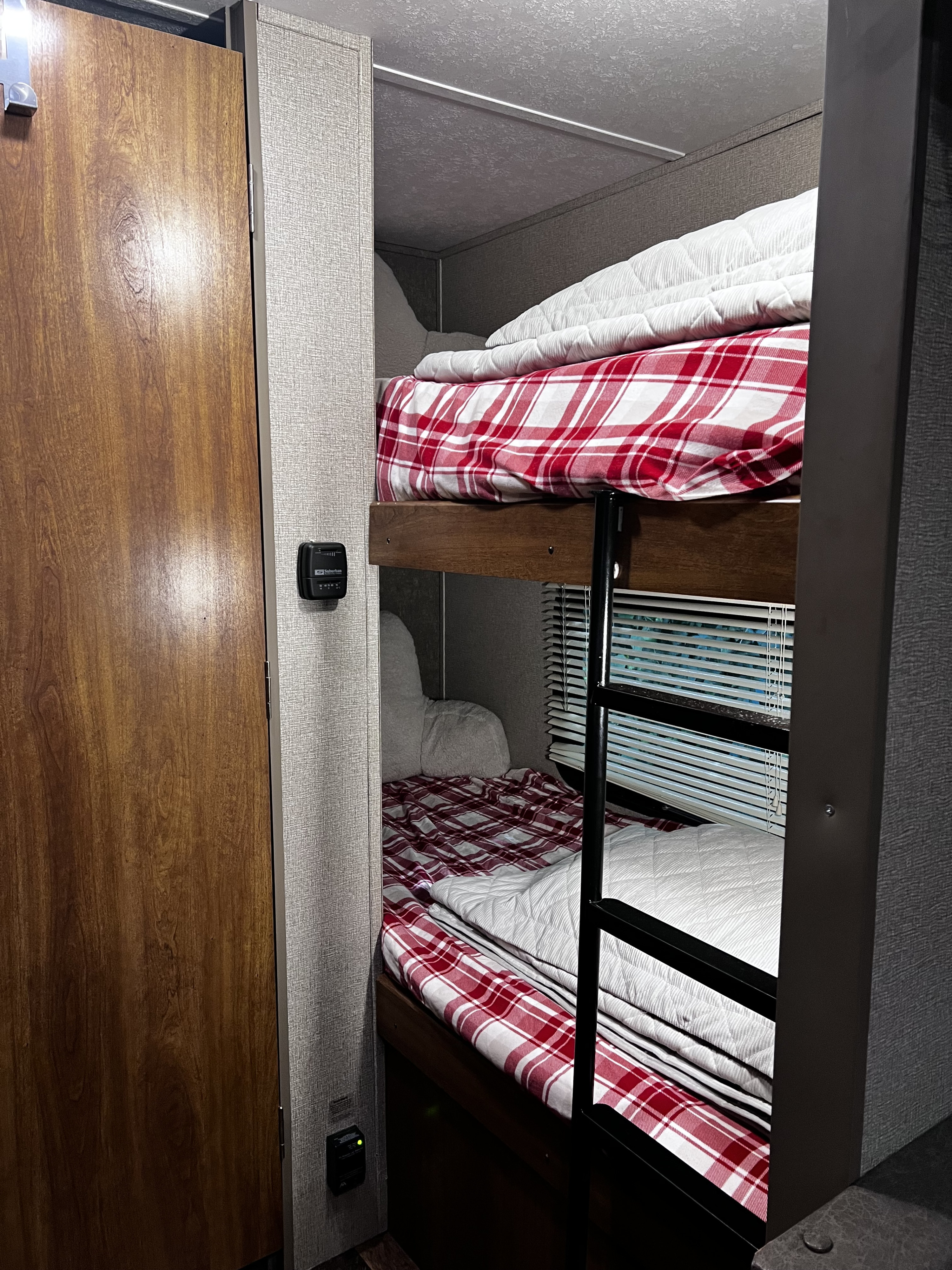 RV rental interior featuring cozy bunk beds with red plaid sheets and white comforters, a ladder, and window blinds.. Keystone RV Summerland Mini 2017