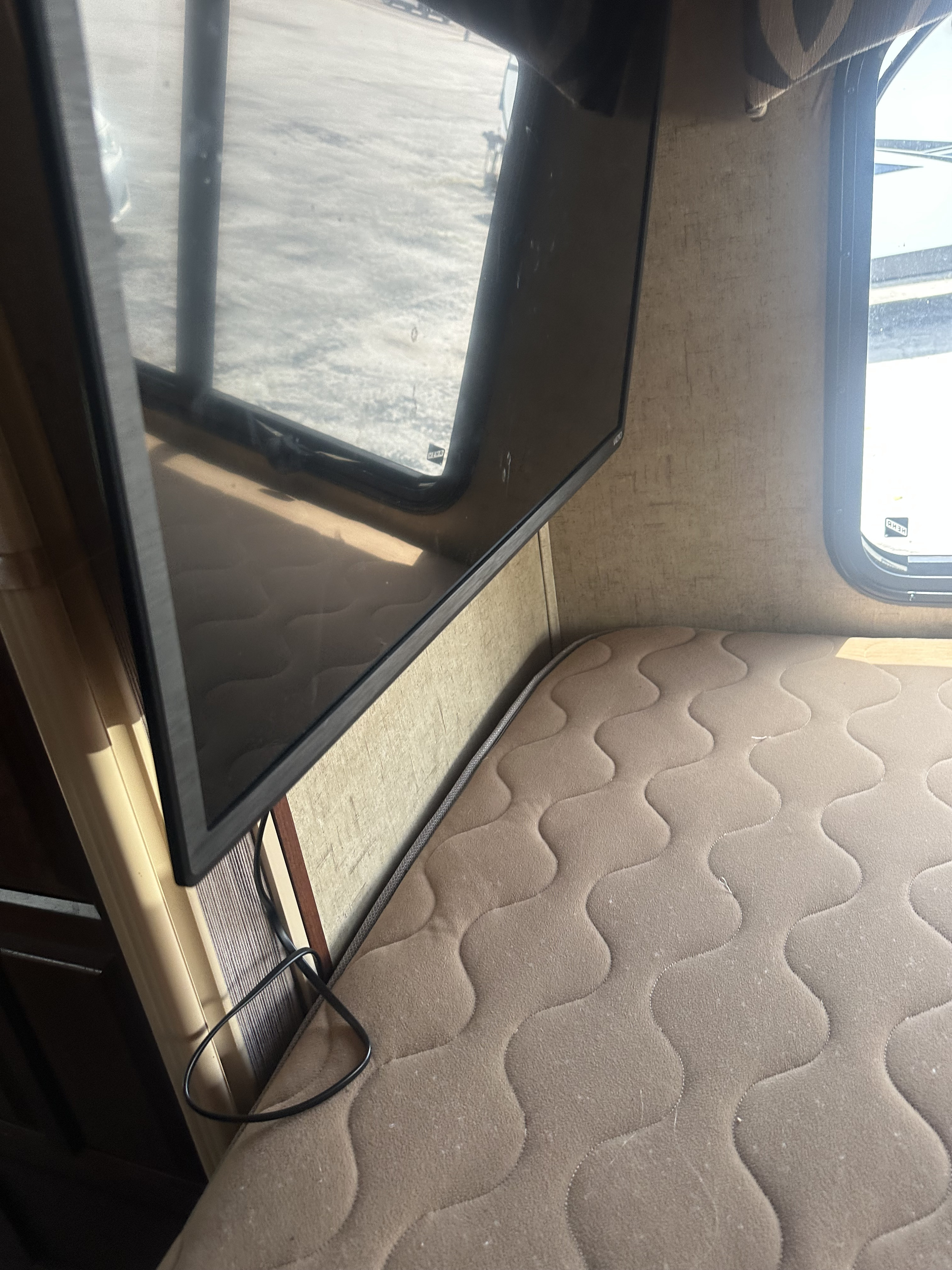 RV rental interior: A mounted TV reflects the outside, next to a window and a comfortable quilted mattress.. Forester MBS 2016