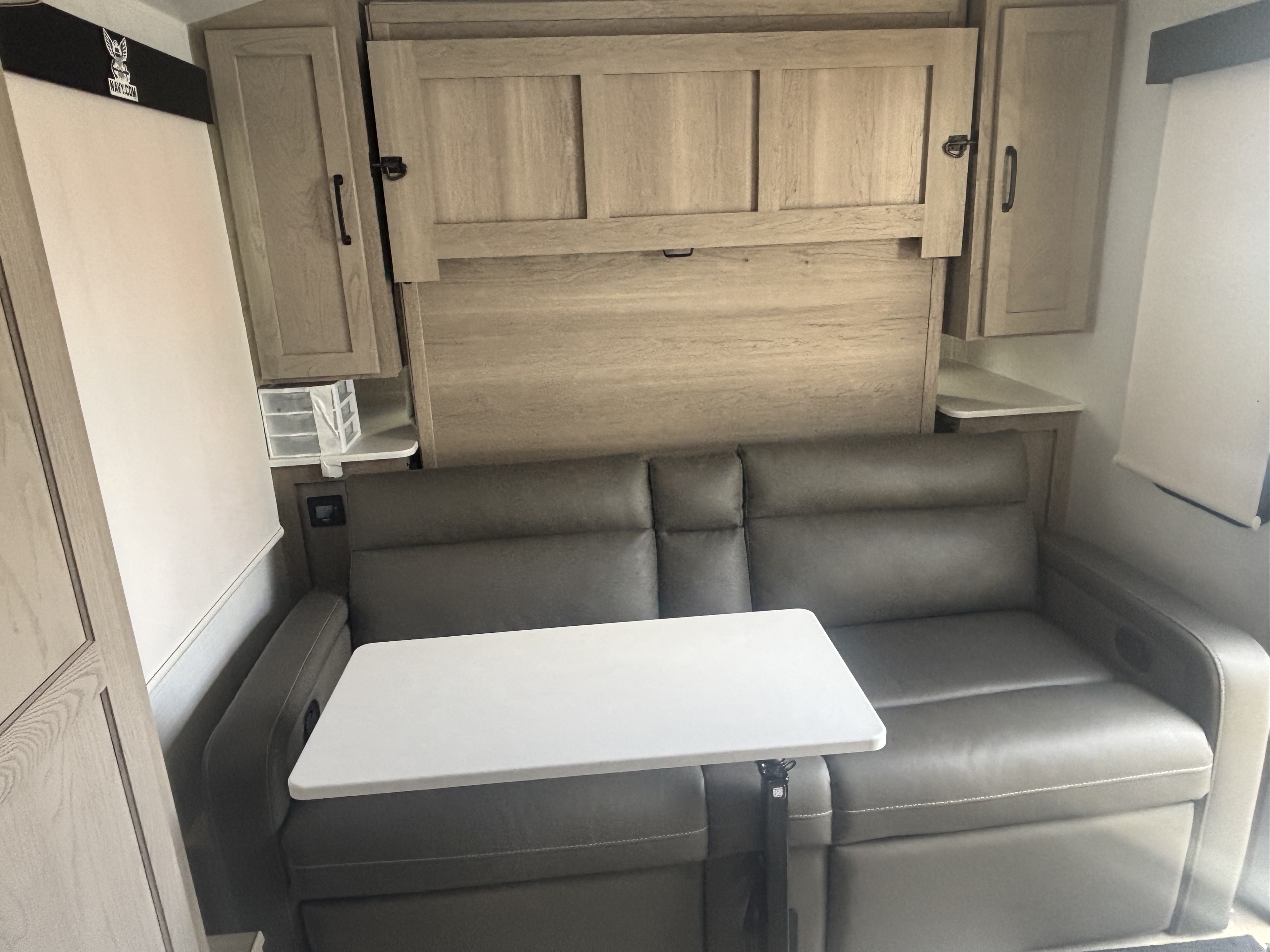 Comfortable RV rental interior featuring a versatile sofa, fold-up murphy bed, and adjustable table.. Forest River Flagstaff E-Pro 2024