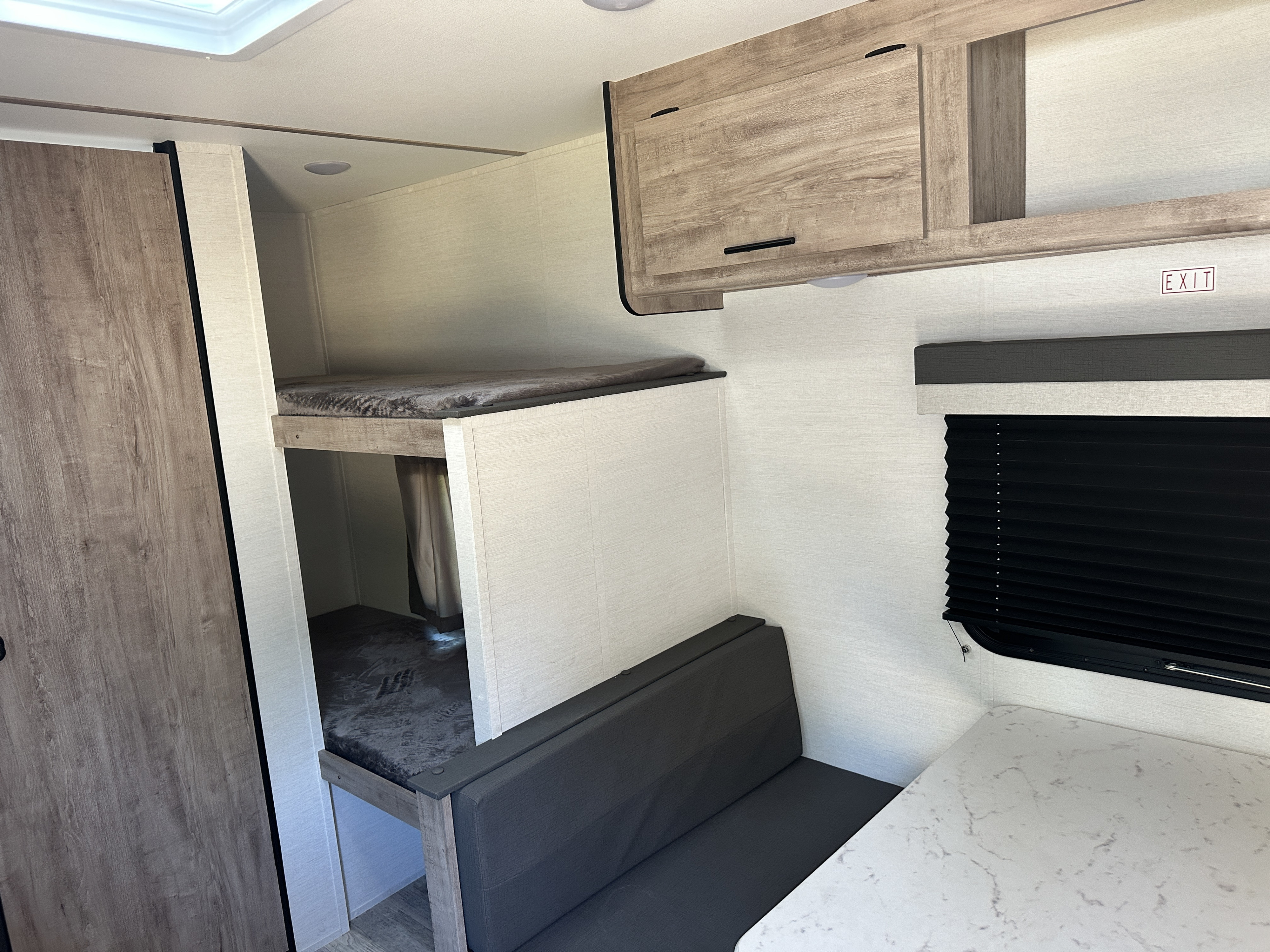 Spacious RV rental interior featuring bunk beds, a dining area, and overhead cabinets. Perfect for trips.. Gulf Stream Enlighten 2025