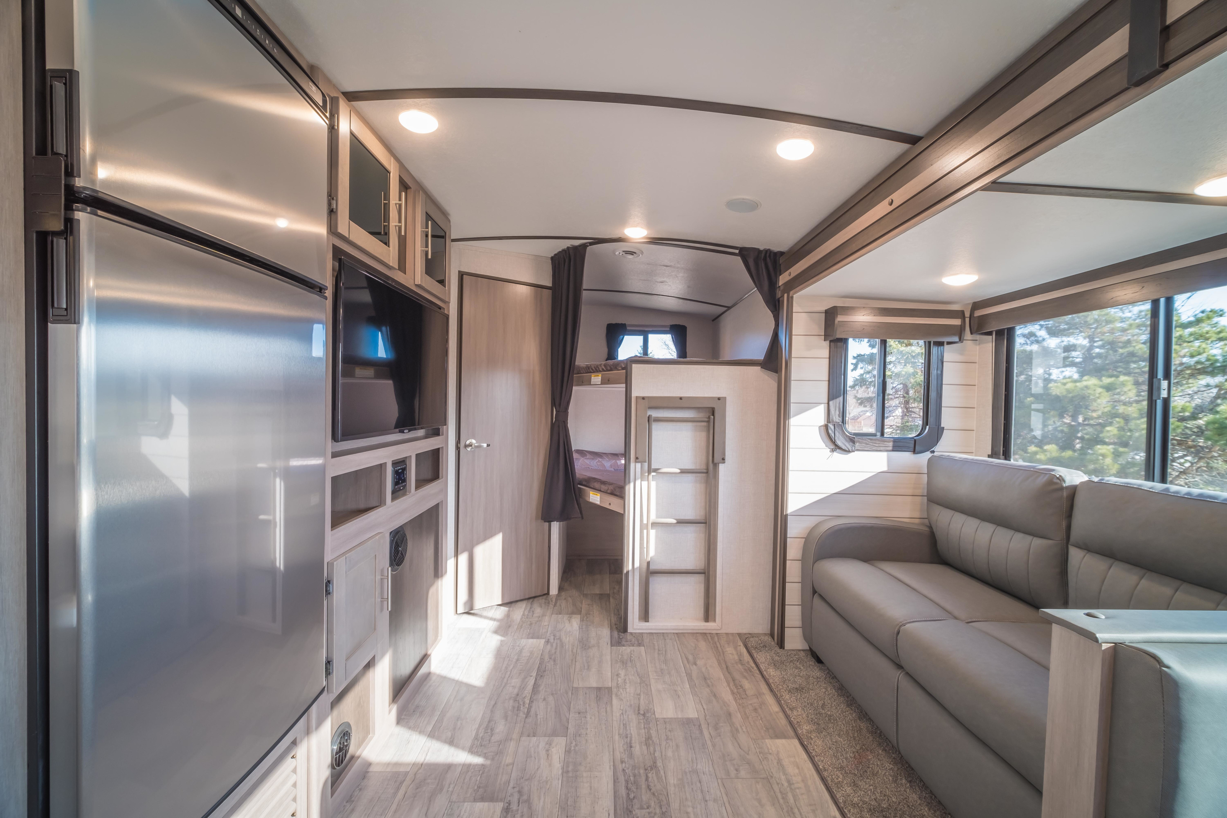 RV rental: Bright, well-appointed travel trailer interior with full kitchen, comfortable sofa, and bunk beds.. Crossroads RV Sunset Trail Super Lite 2021