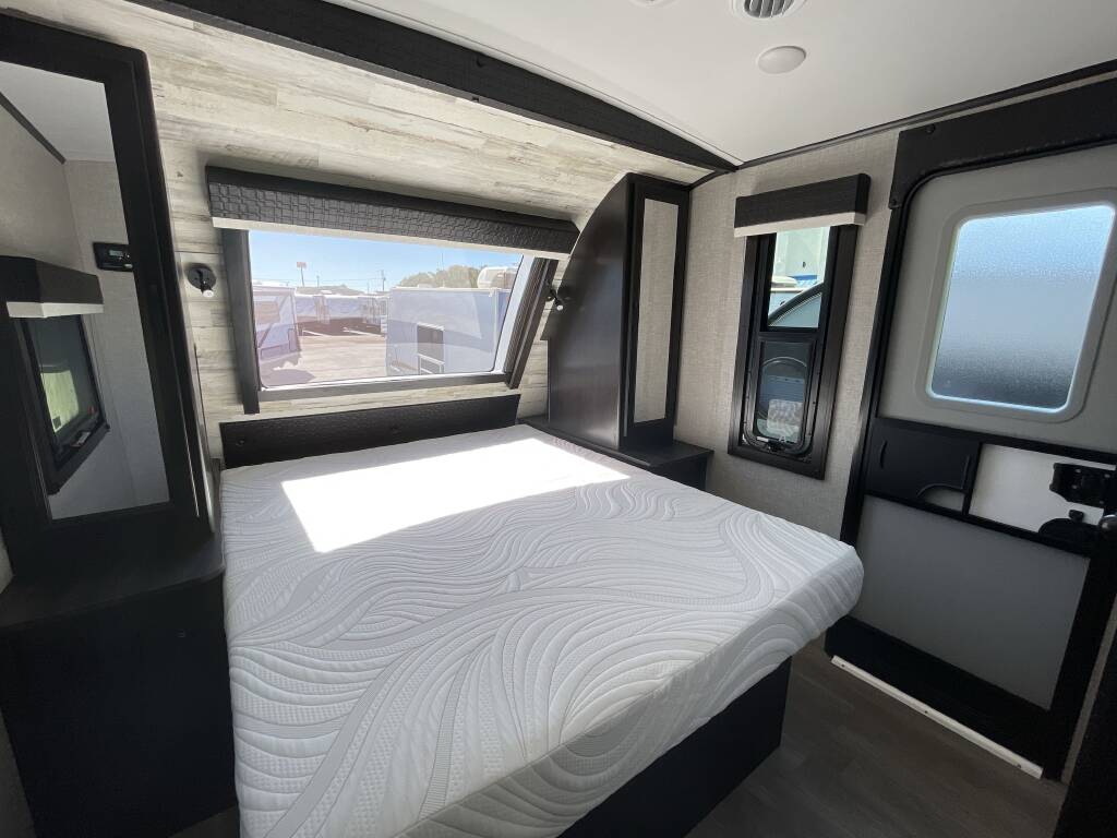 Spacious RV bedroom featuring a comfortable bed, large window, and entry door, ideal for your next RV rental trip.. Jayco White Hawk 2022