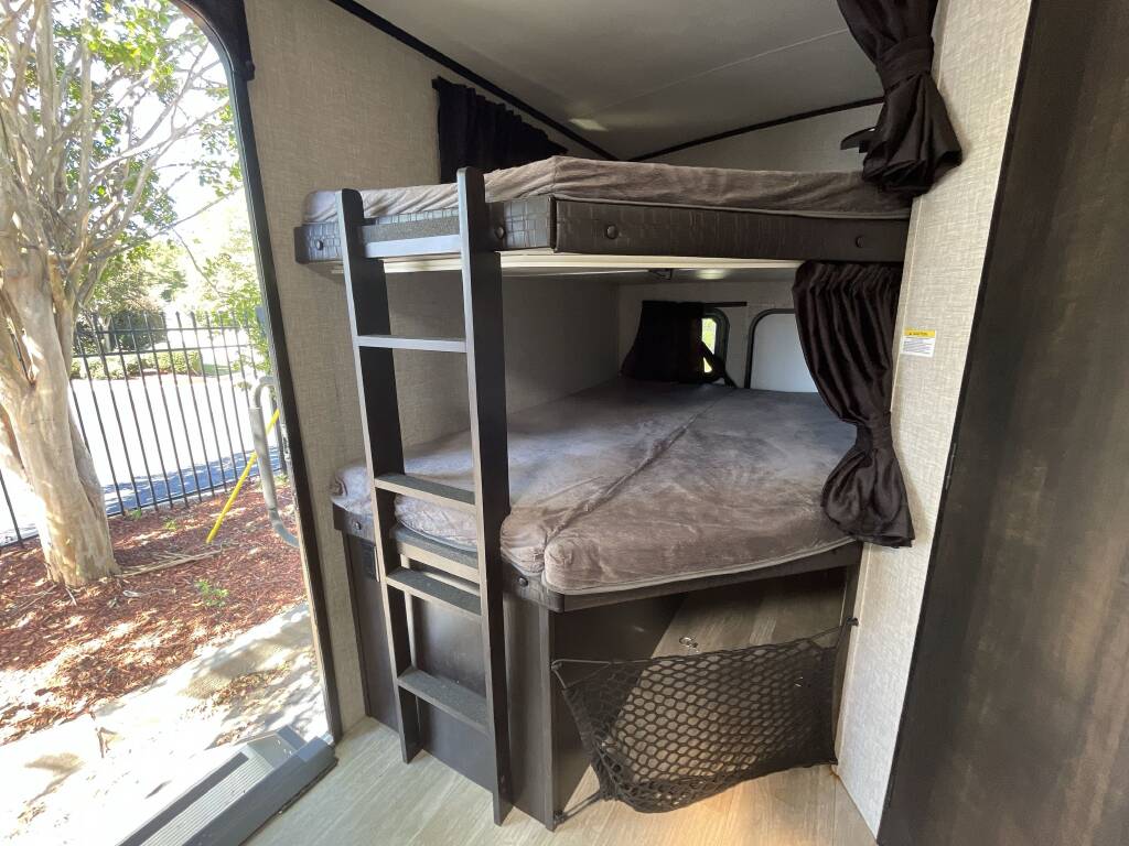 Cozy RV rental bunk beds feature a ladder, privacy curtains, and storage net, perfect for family trips.. Jayco White Hawk 2022