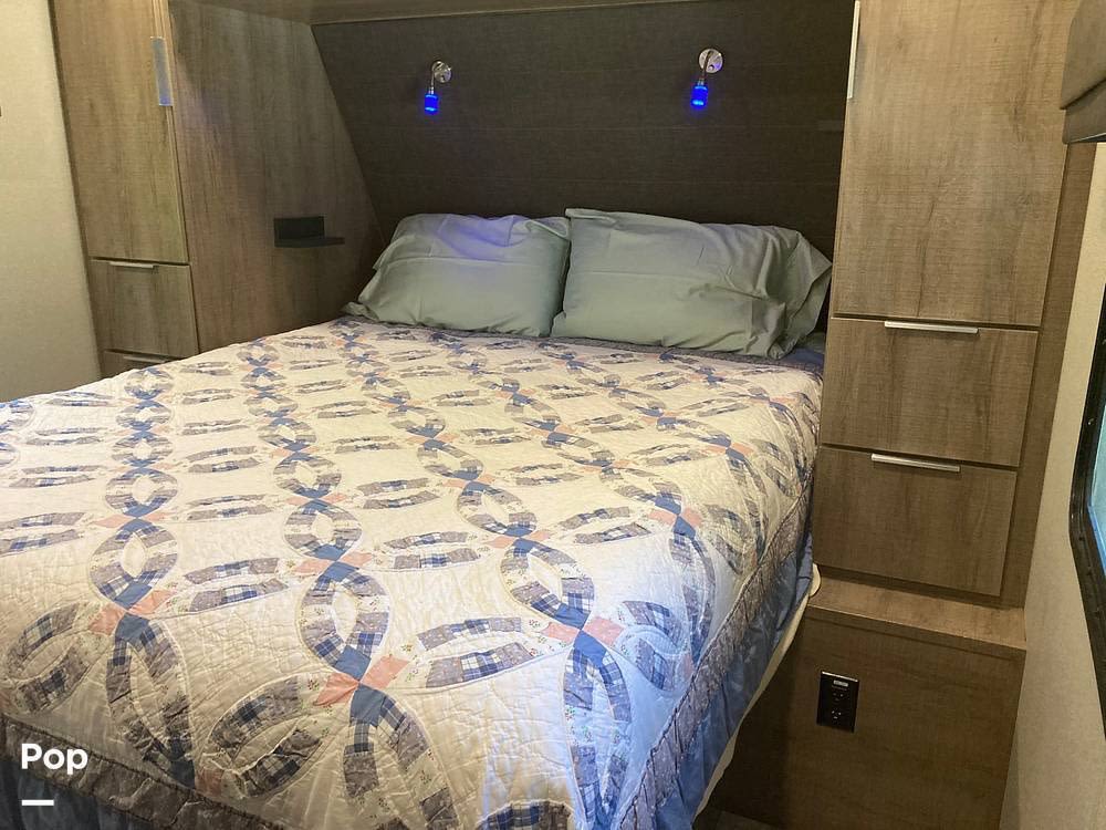 Inside an RV rental: A compact bedroom featuring a comfortable bed with a unique quilt, ample storage, and bedside lights.. Grand Design Imagine 2020