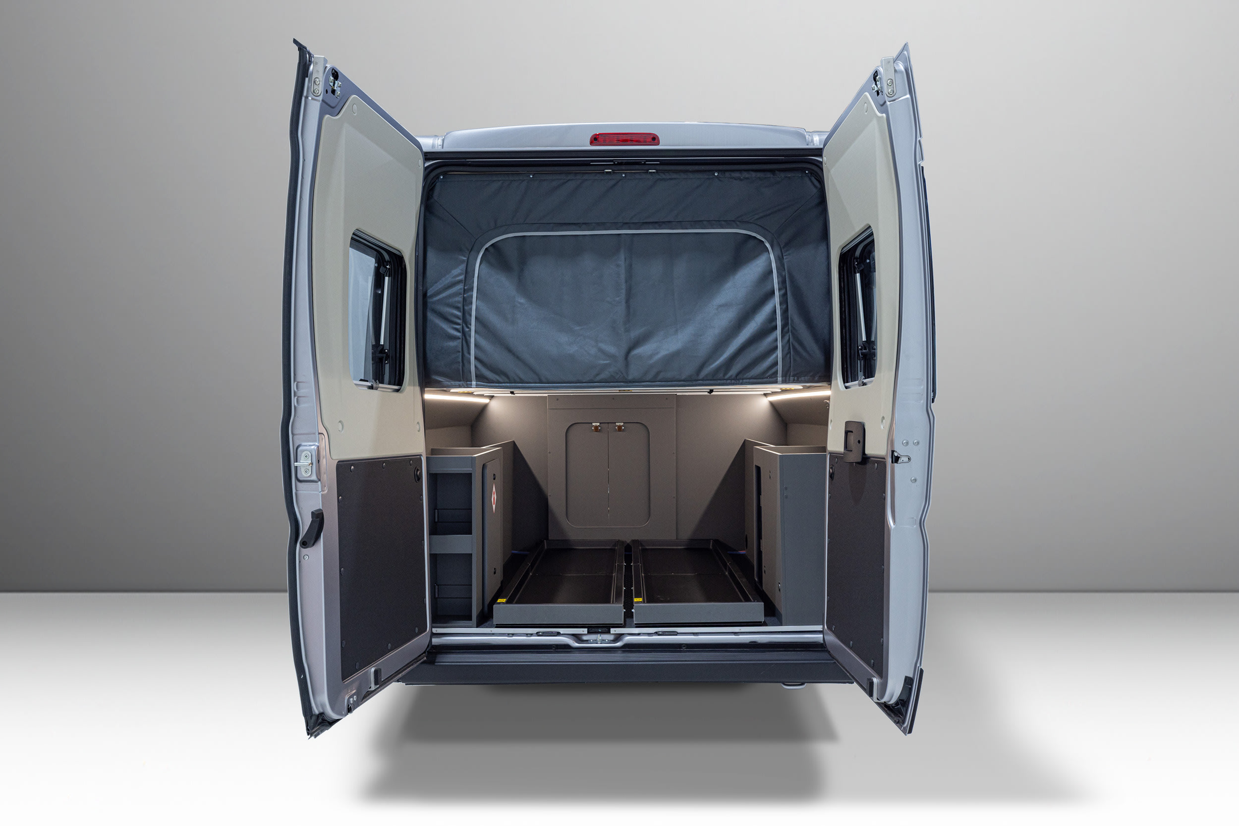 The open rear of this RV rental highlights its modular interior with pull-out storage trays, shelving, and a flexible sleeping area.. Auto Trail Expedition 68 XL 2026