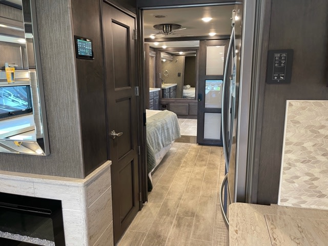 Spacious RV rental interior: view from the living area into the bedroom, featuring a fireplace & modern controls.. Thor Tuscany 2022