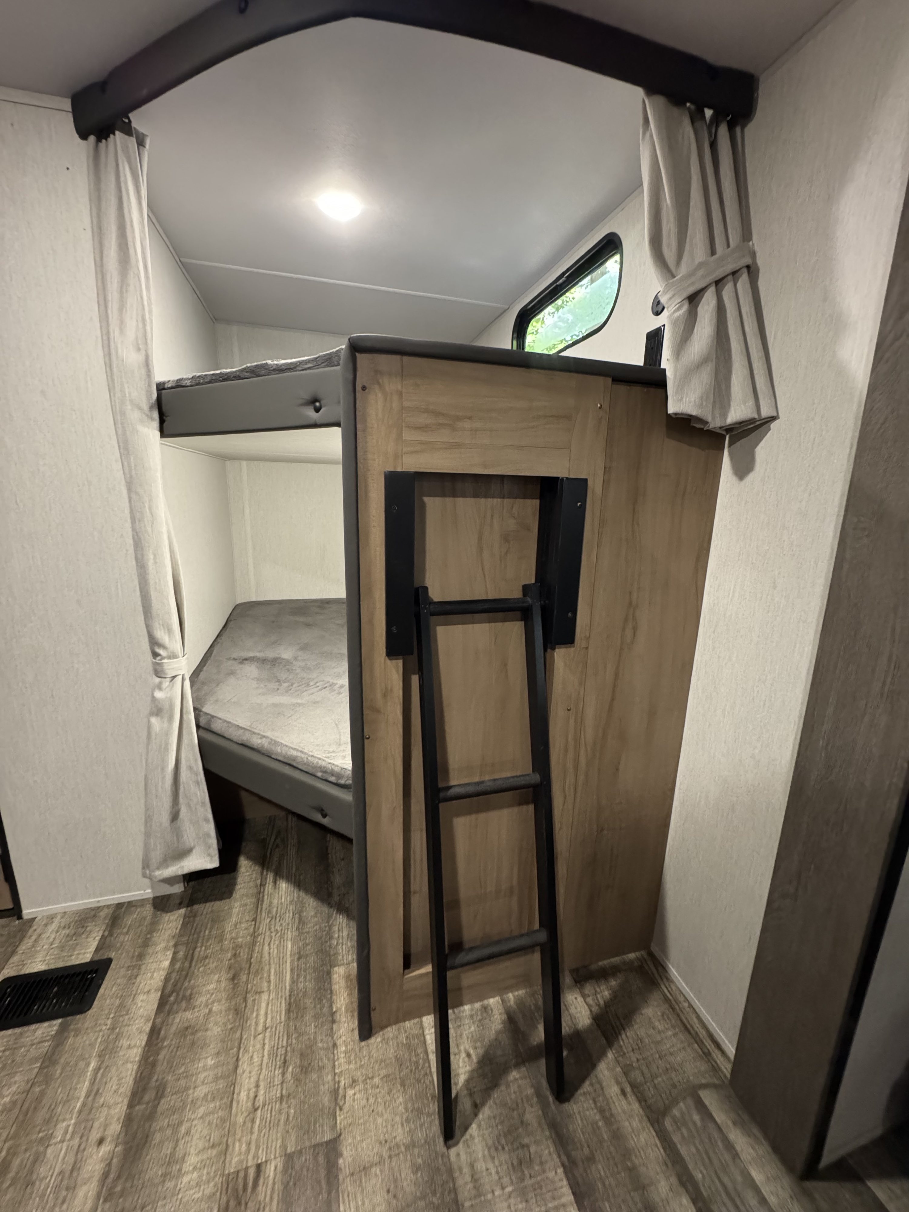 RV rental interior: bunk beds with mattresses, a ladder, and privacy curtains create a cozy sleeping area.. Forest River Cherokee Grey Wolf 2024