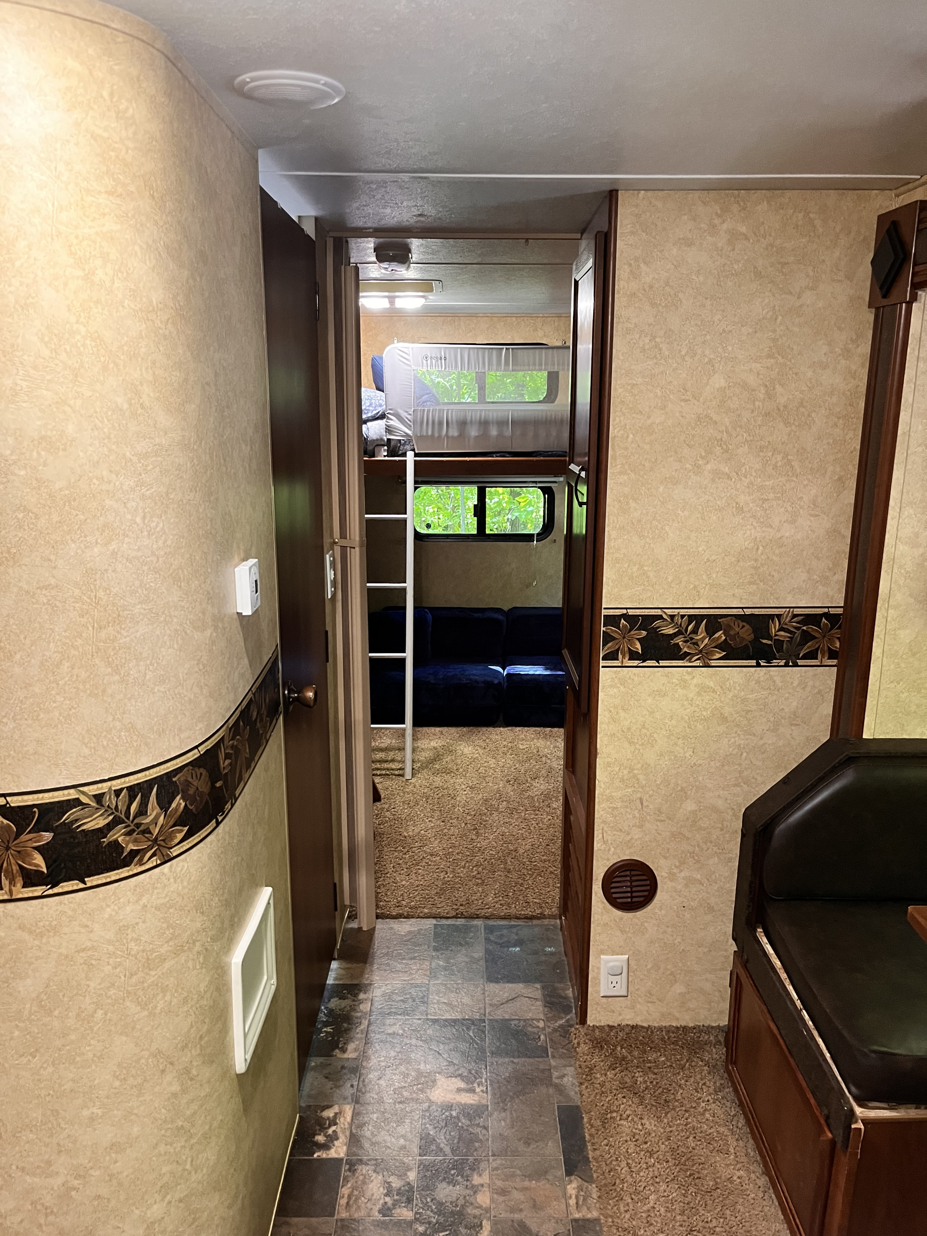 RV rental interior view: Hallway leads to a bunk bed area with sofa, and a dining booth is on the right. Features tile & carpet flooring.. Forest River Lacrosse Luxury Lite 2012