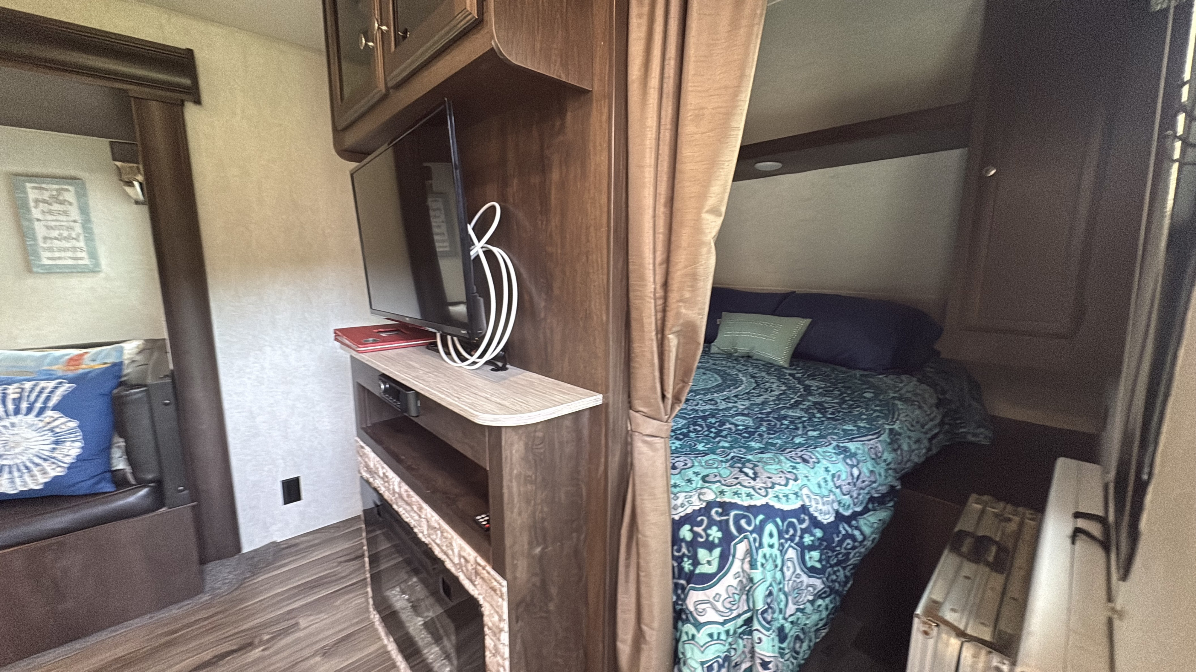 Interior of an RV rental showing a dining booth, entertainment unit with TV, and a cozy bedroom behind a curtain.. Starcraft Autumn Ridge Outfitter 2018