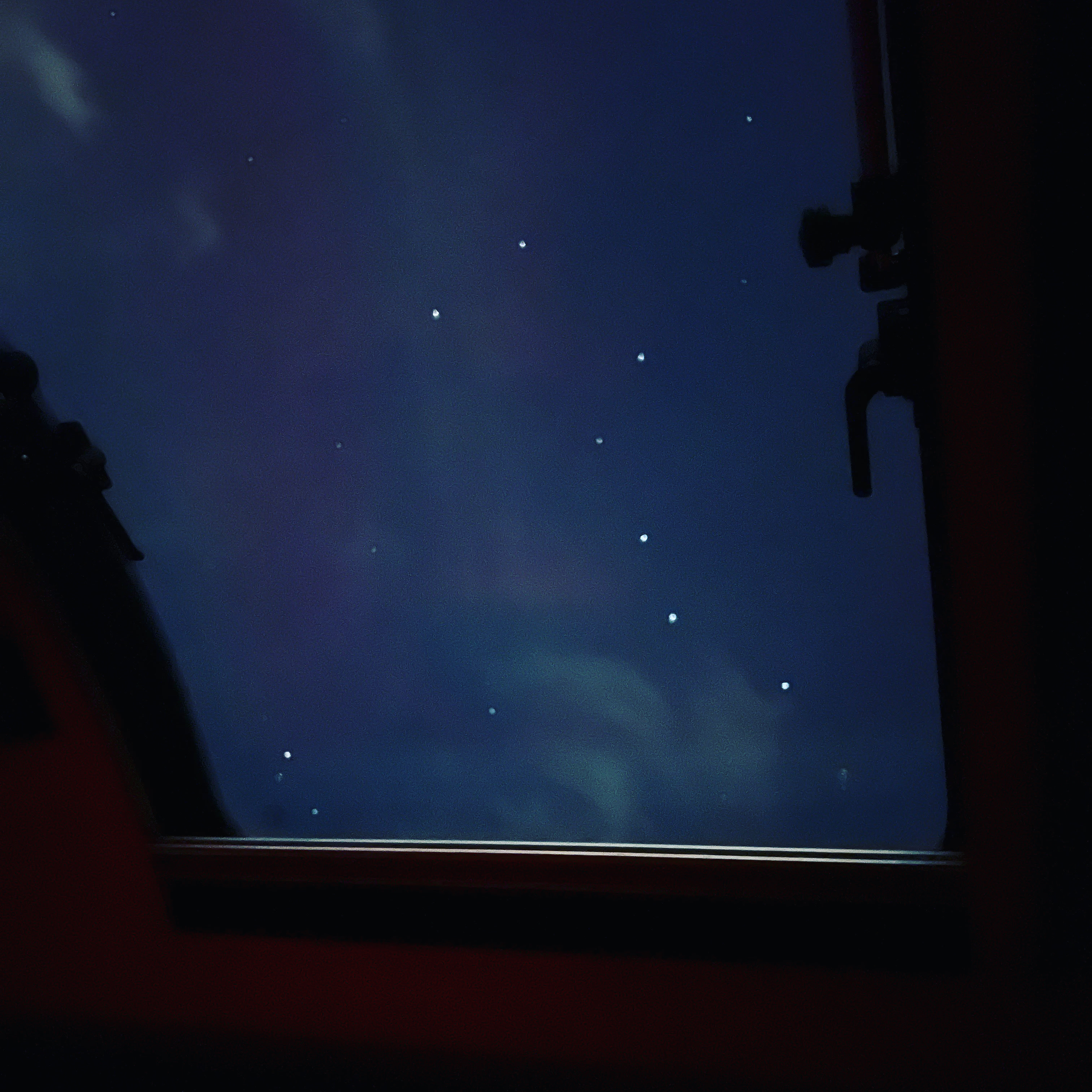 Stargazing in your rv rental: deep blue night sky with bright scattered points and faint clouds, framed by a window.. nuCamp T@G 2021