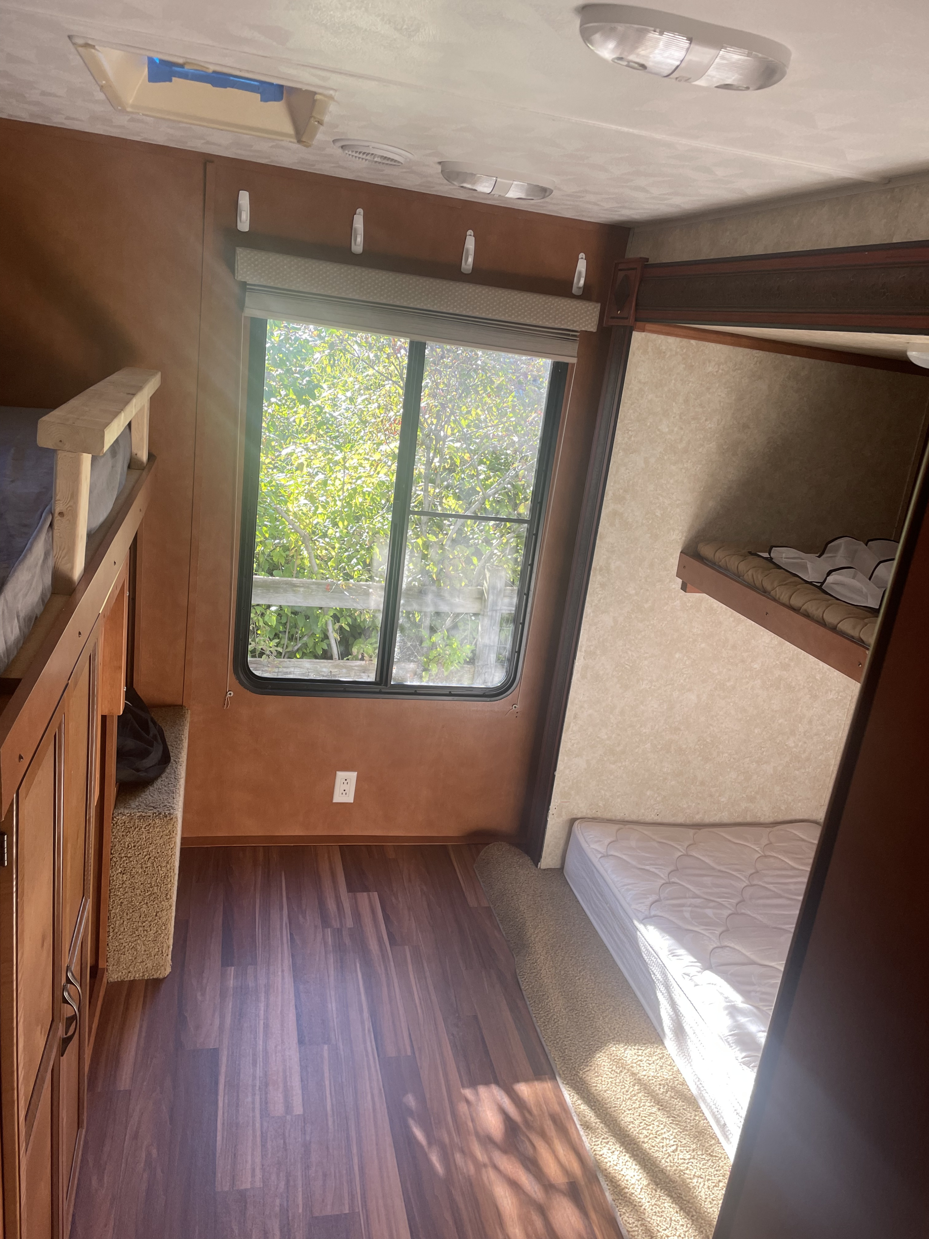 Spacious RV rental interior with comfortable bunk beds, a bright window view, and a mix of wood and carpet flooring.. Gulf Stream Conquest 2014