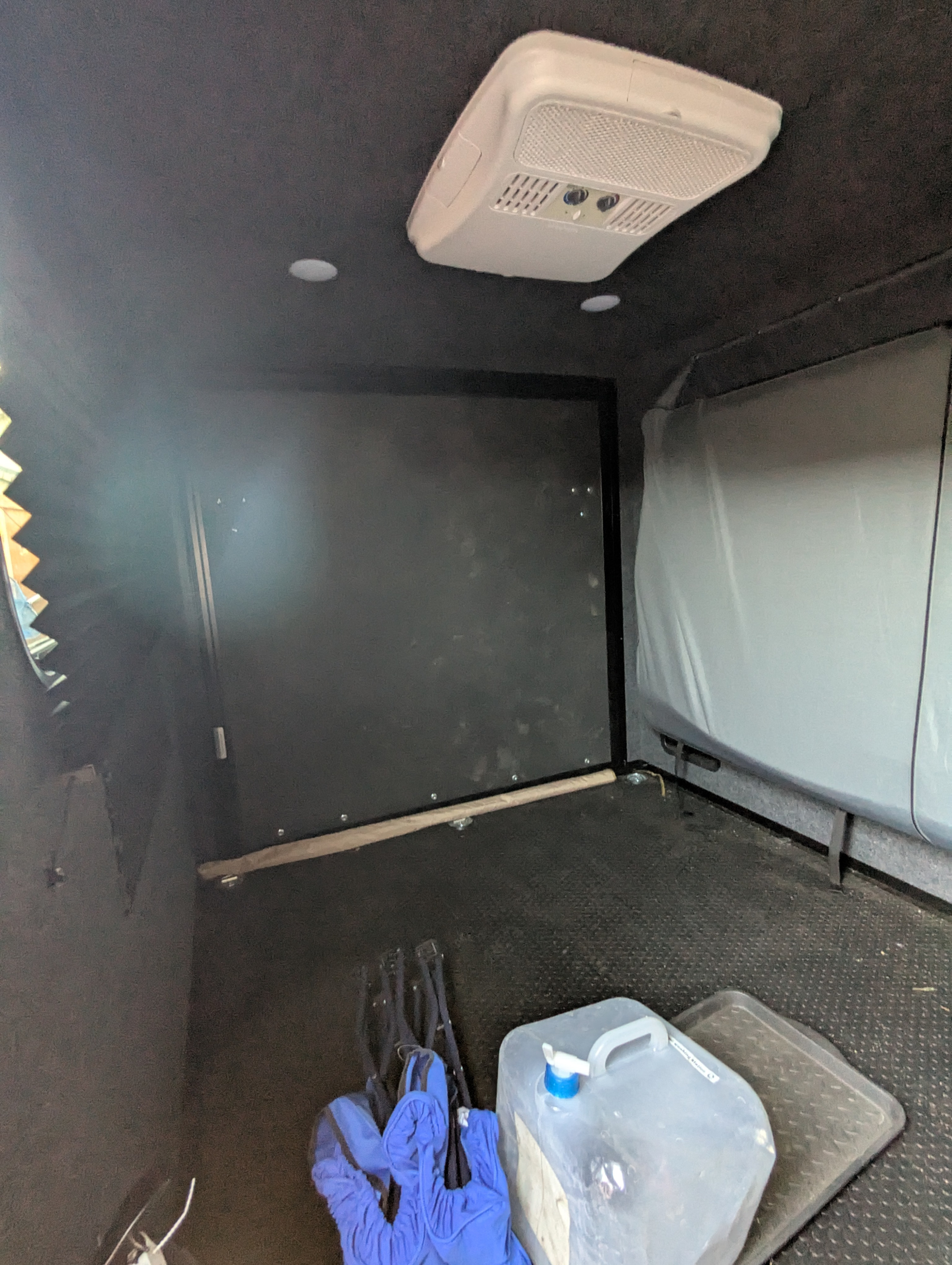 Compact RV rental interior with AC unit, storage, and water jug. Ideal for mobile living and travel.. InTech RV Flyer 2023