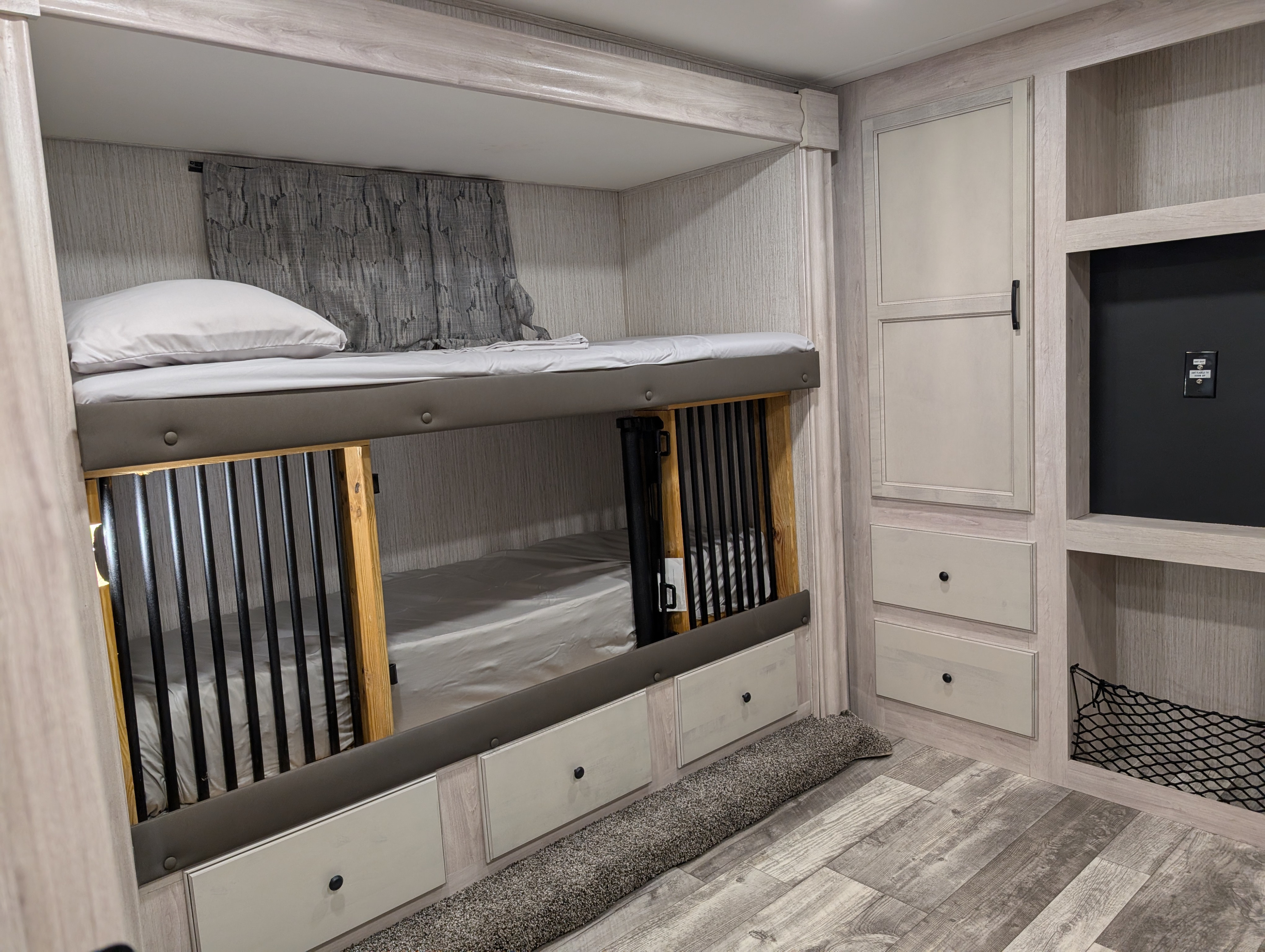 Inside an **RV rental**: light wood interior with **bunk beds**, an integrated **dog kennel**, storage, and a TV mount.. Forest River Sandpiper 2022