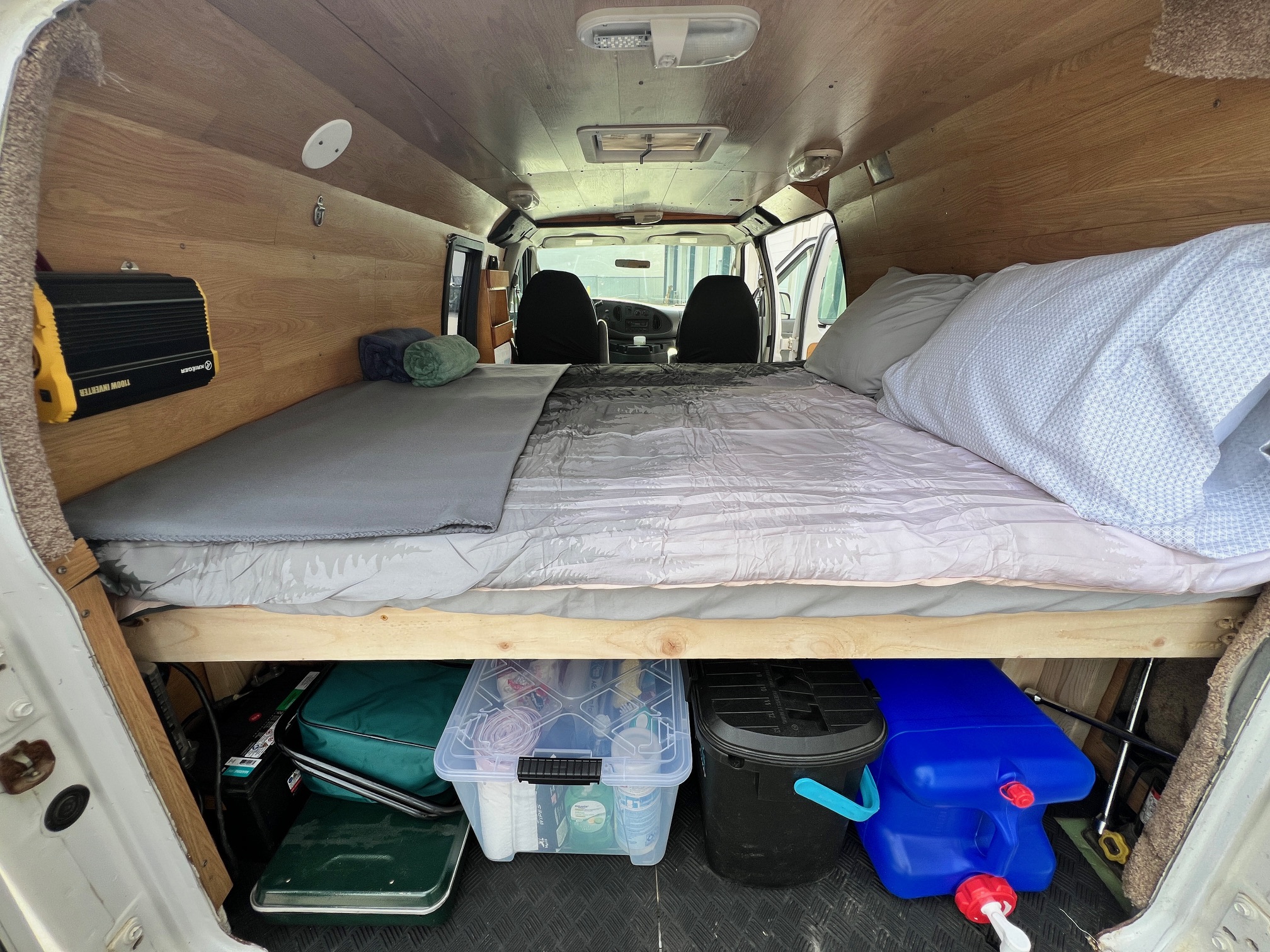 This RV rental shows a comfy camper van interior with a bed, power inverter, and organized under-bed storage, ideal for mobile adventures.. Ford Econolline 250s 2006