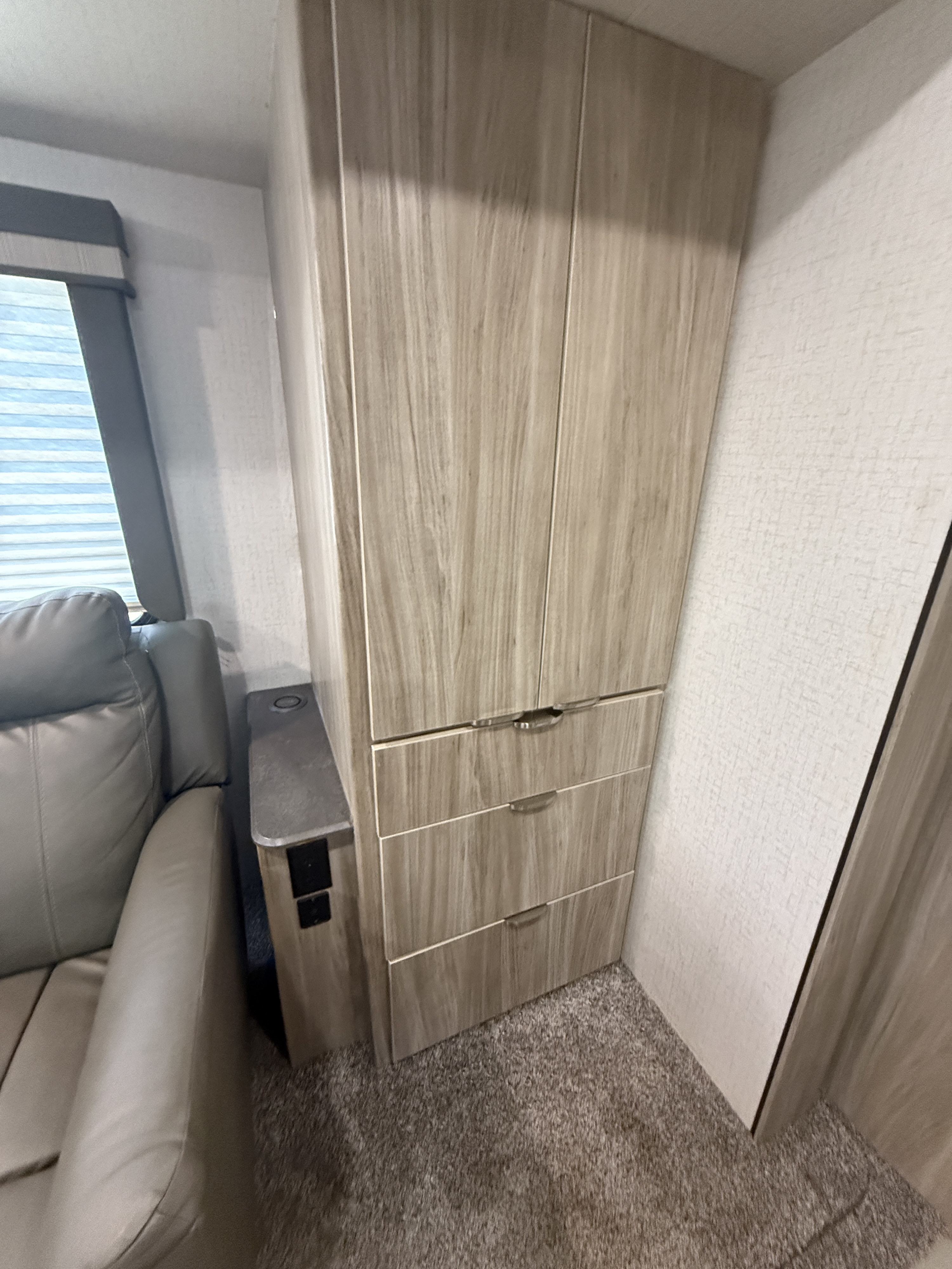 RV rental interior featuring a modern wood storage cabinet, comfortable sofa, and side console with charging ports.. Winnebago Mini Winnie 2022