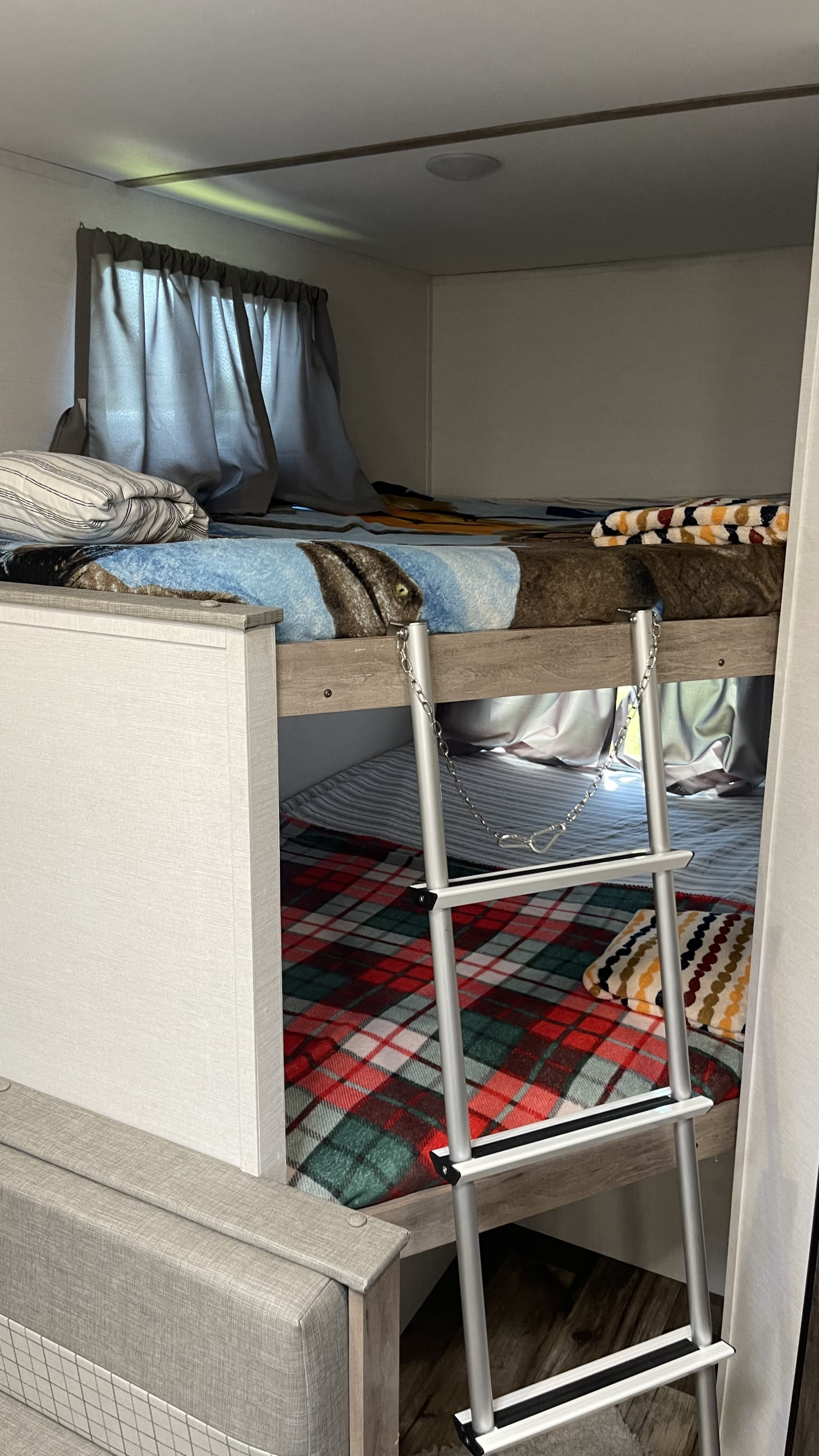 Spacious RV rental bunk beds with cozy bedding and a ladder, perfect for family sleeping arrangements.. Gulf Stream Grand River 22Mb 2024